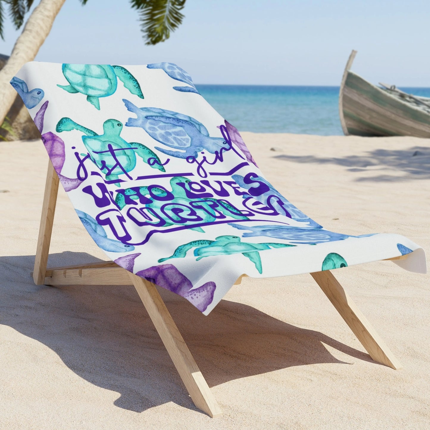 a white beach towel with turquoise, blue and purple sea turtles that says Just a Girl Who Loves Sea turtles laying on a lounge chair on the beach