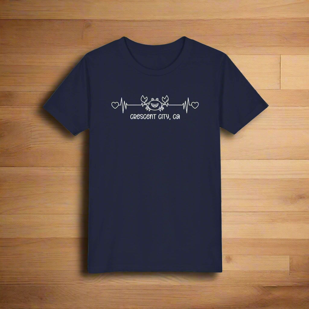 Navy Child t-shirt with a smiley crab on a heartbeat line with hearts at both ends and “Crescent City, CA” underneath the design.