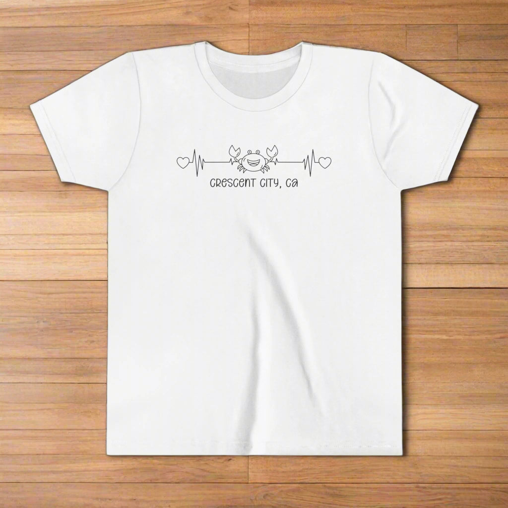 White Youth t-shirt with a smiley crab on a heartbeat line with hearts at both ends and “Crescent City, CA” underneath the design.