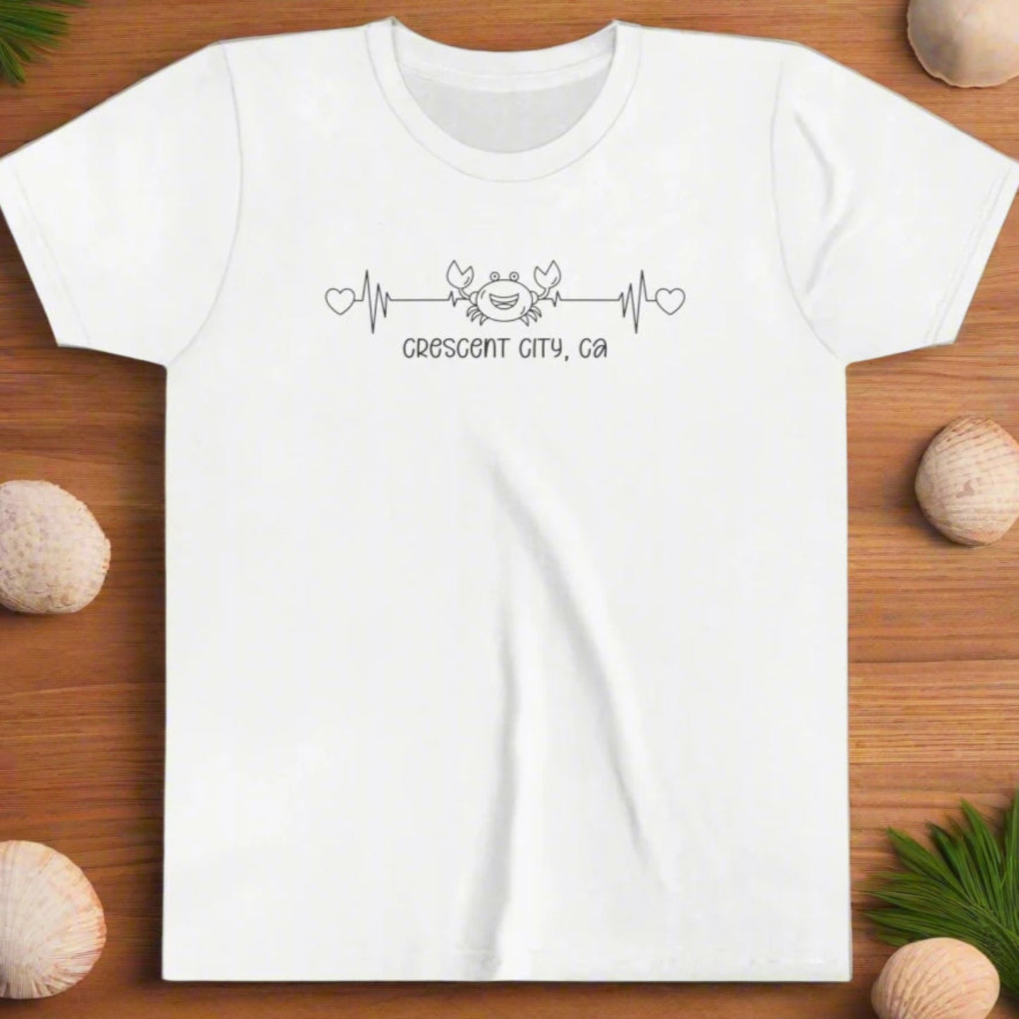 White Youth t-shirt with a smiley crab on a heartbeat line with hearts at both ends and “Crescent City, CA” underneath the design.