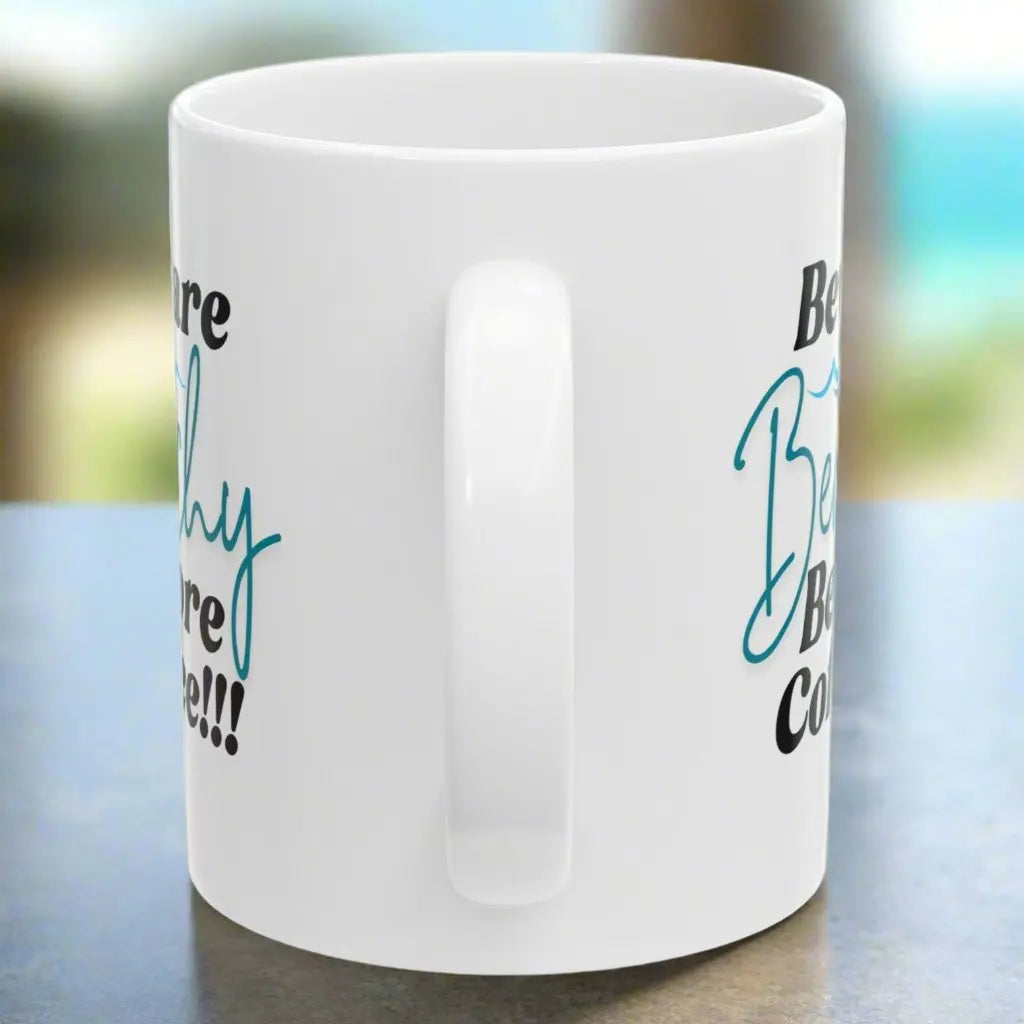 Side view of White coffee mug that says Beware Beachy Before coffee with wave image.