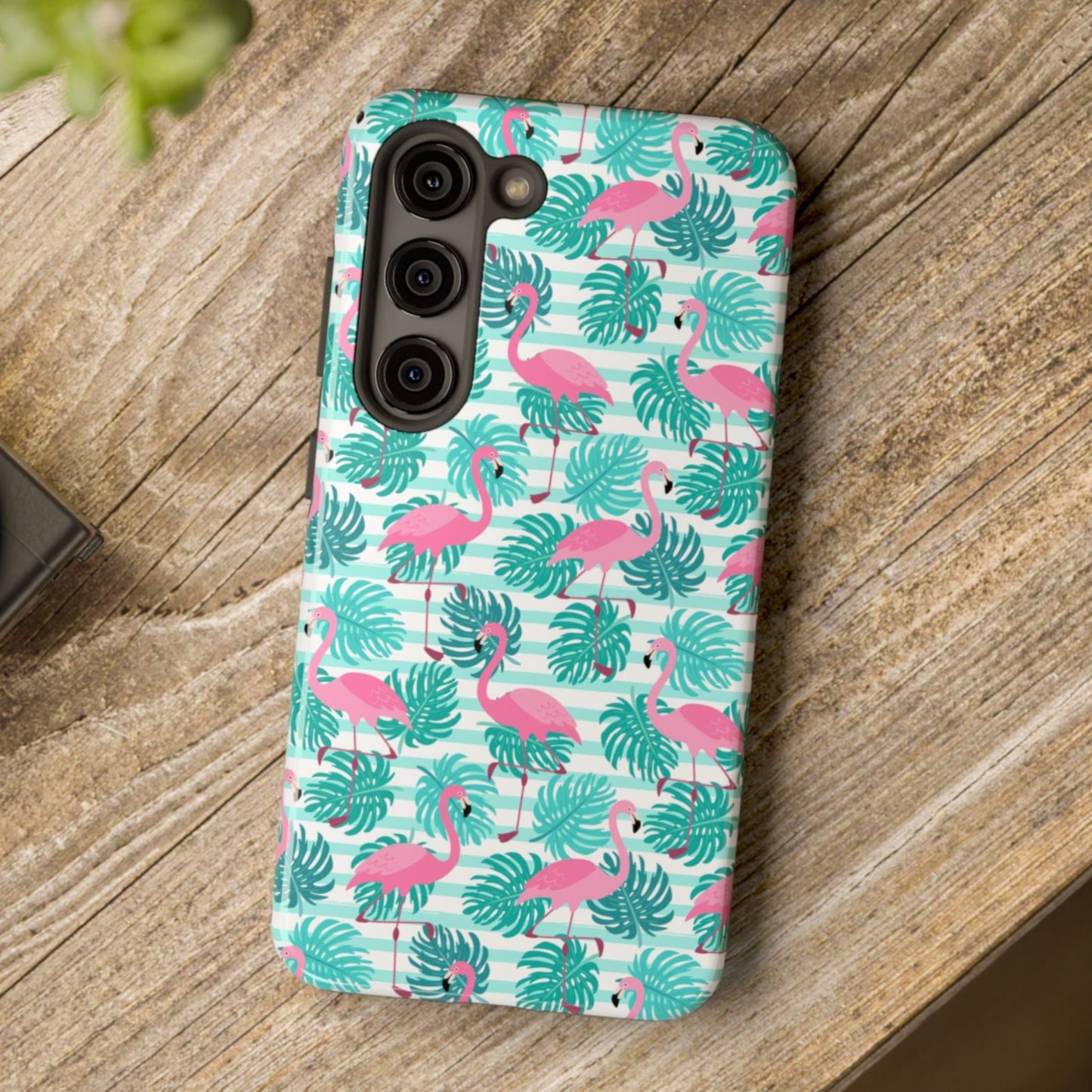 Phone case with flamingo and leaf pattern on a wooden surface