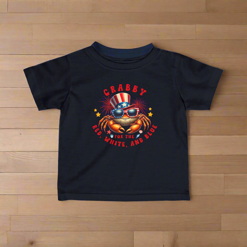 Navy Infant t-shirt with a crab wearing an American flag top hat surrounded by fireworks and seashells with the phrase “Crabby for the Red, White, and Blue.”