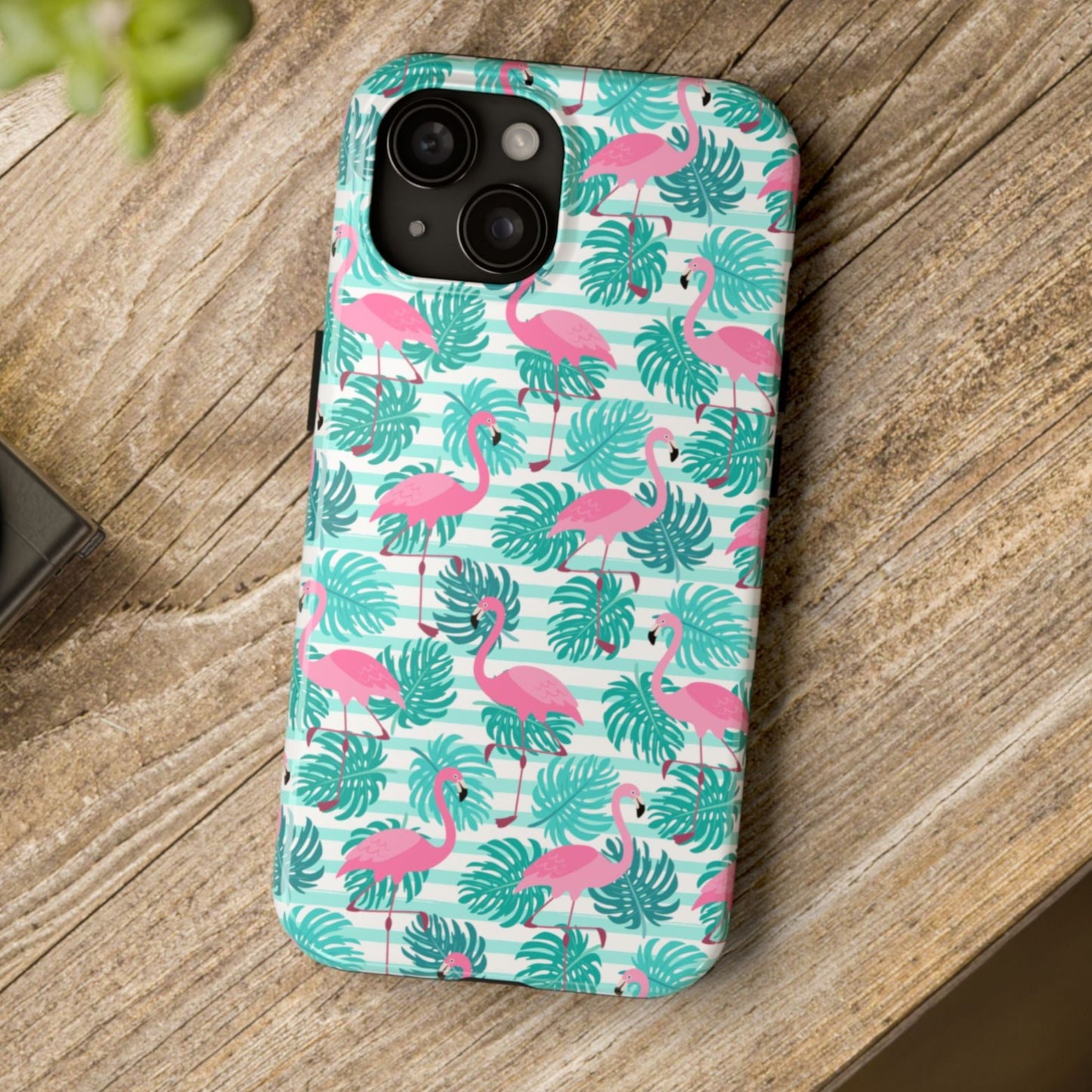 Phone case with flamingo and leaf pattern on a wooden surface
