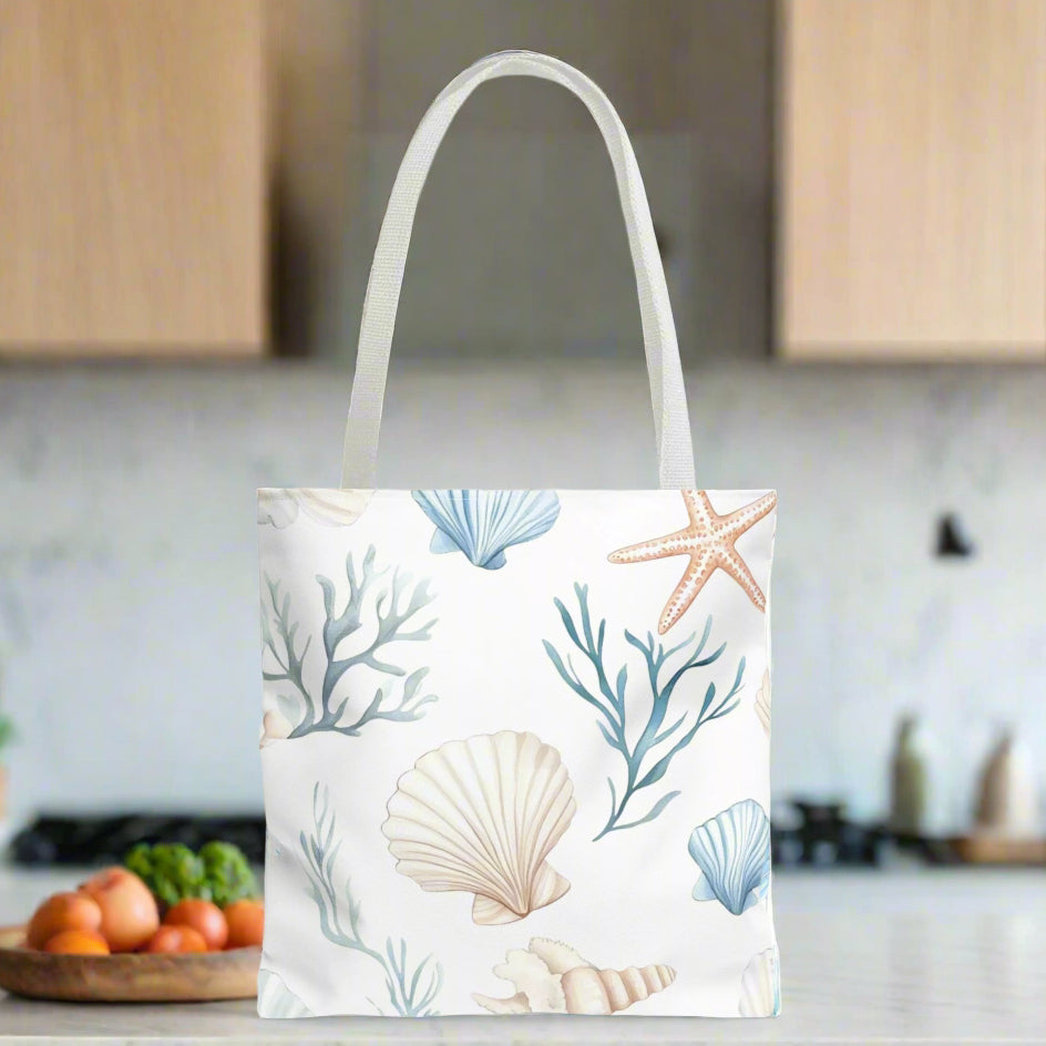 16" x 16" White tote bag with pastel blue and coral seashells, starfish, and underwater plants, with white handles.