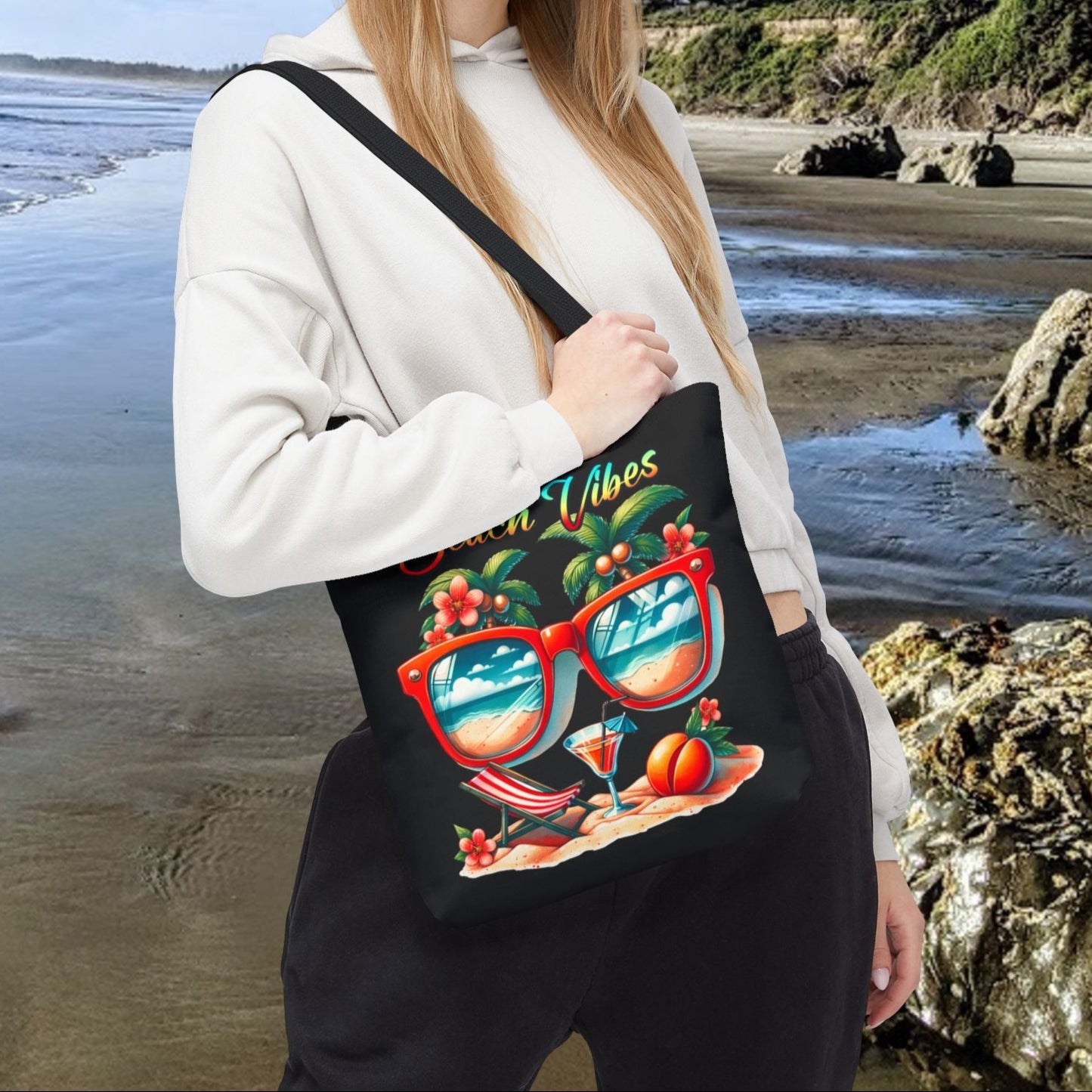 Black 13" x 13" Tote bag featuring sunglasses with ocean and beach scene reflections, palm trees coming out of the glasses, a beach chair and cocktail on the sand, with the phrase "Beach Vibes" in a retro rainbow gradient font.