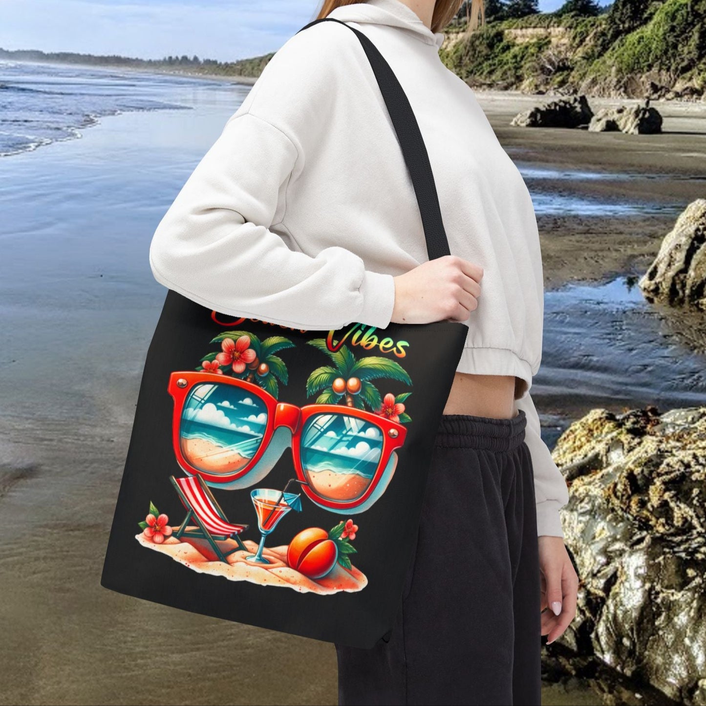 16" x 16" Black Tote bag featuring sunglasses with ocean and beach scene reflections, palm trees coming out of the glasses, a beach chair and cocktail on the sand, with the phrase "Beach Vibes" in a retro rainbow gradient font.