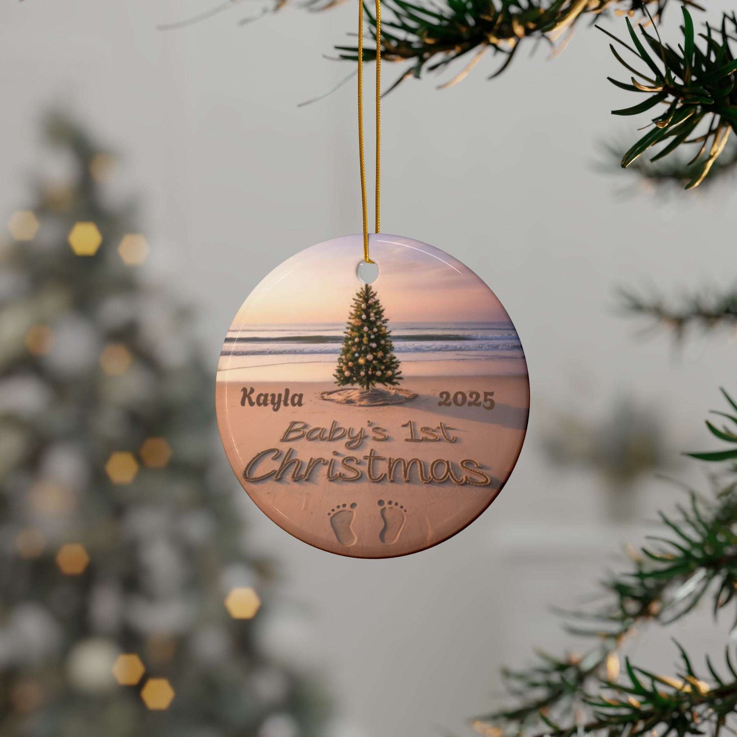 Round Christmas ornament with beach scene and 'Baby's 1st Christmas' text, hanging on a tree.