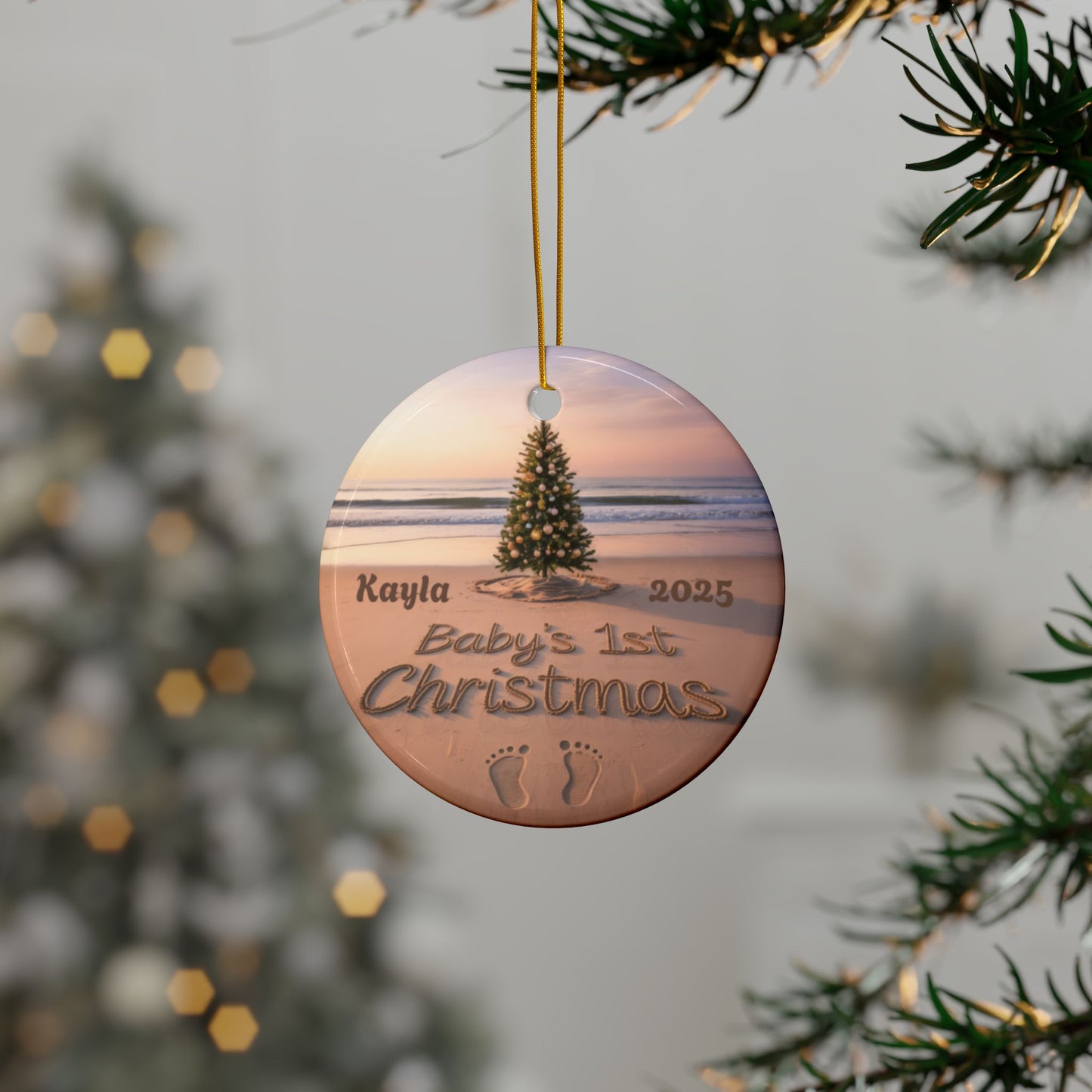 Round Christmas ornament with beach scene and 'Baby's 1st Christmas' text, hanging on a tree.