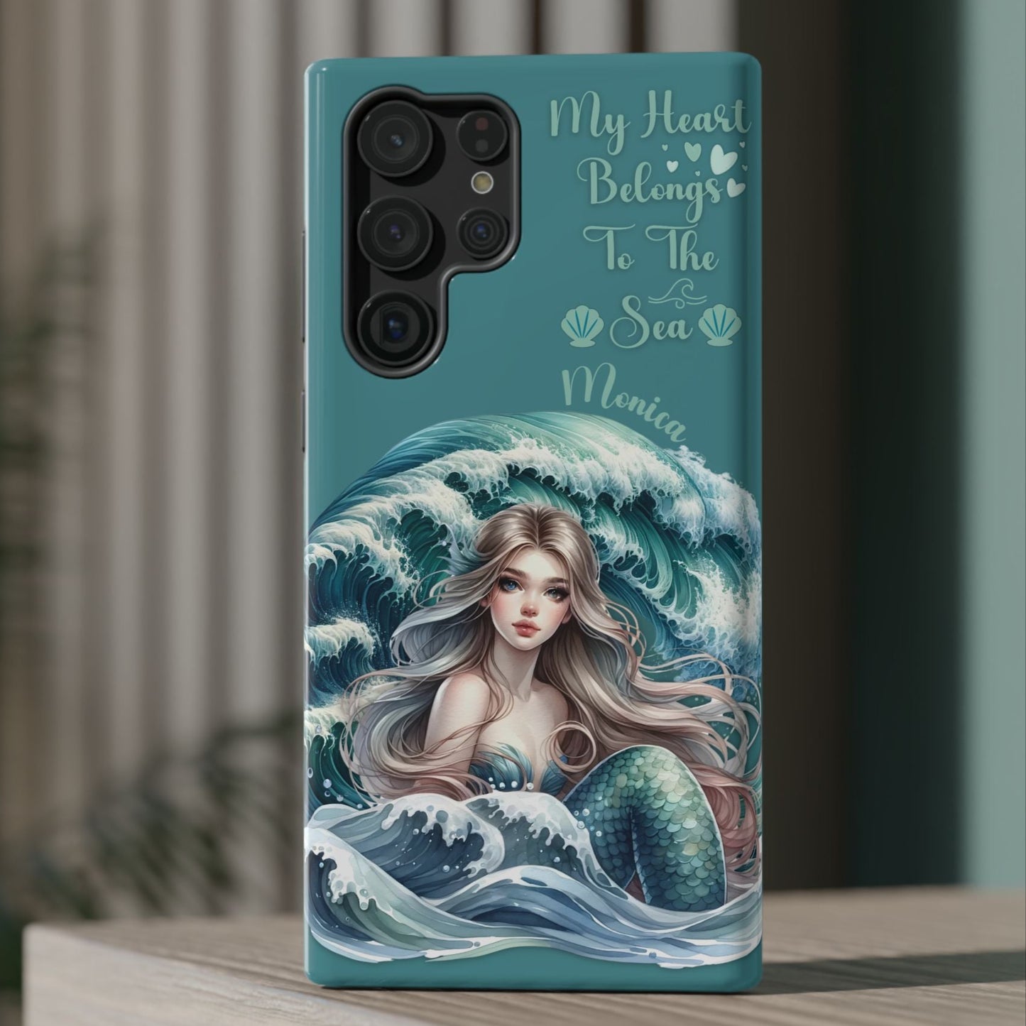 Phone case with mermaid design and text on a wooden surface