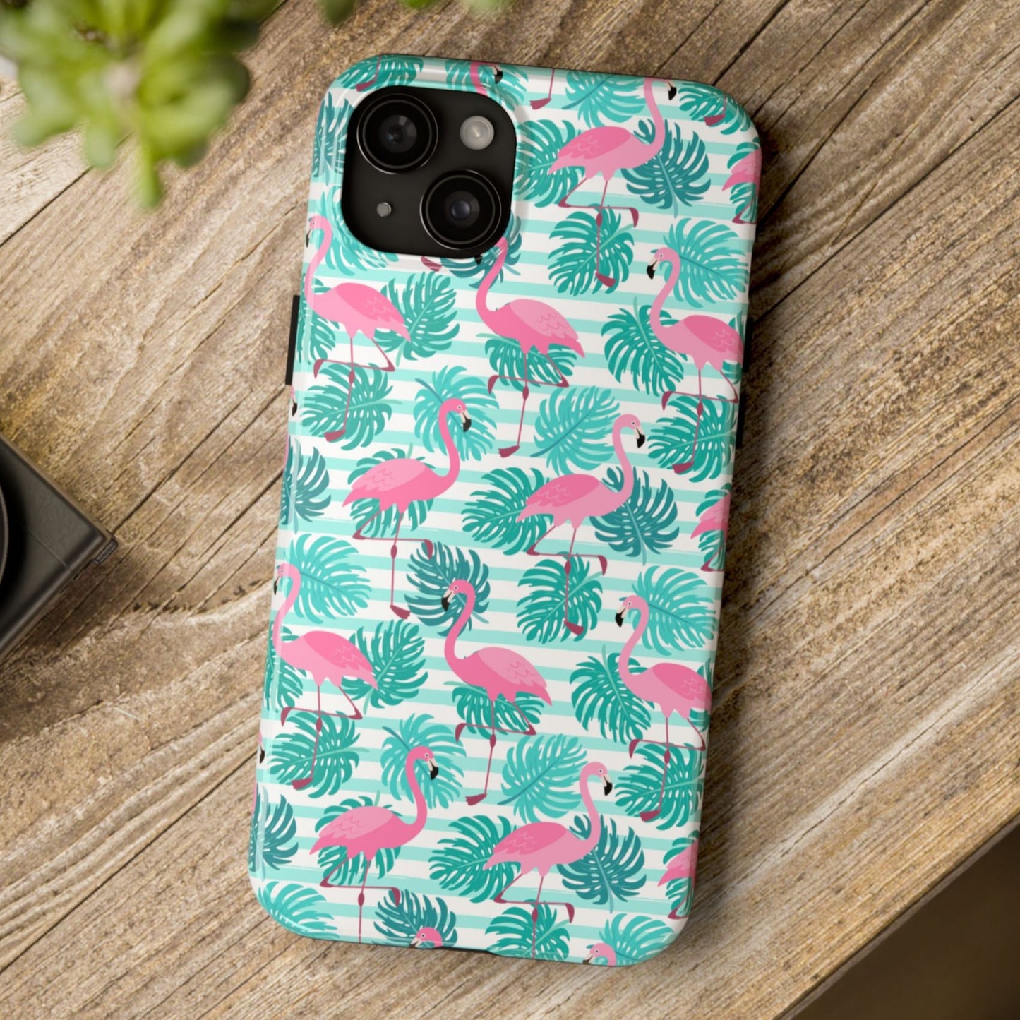 Phone case with flamingo and leaf pattern on a wooden surface
