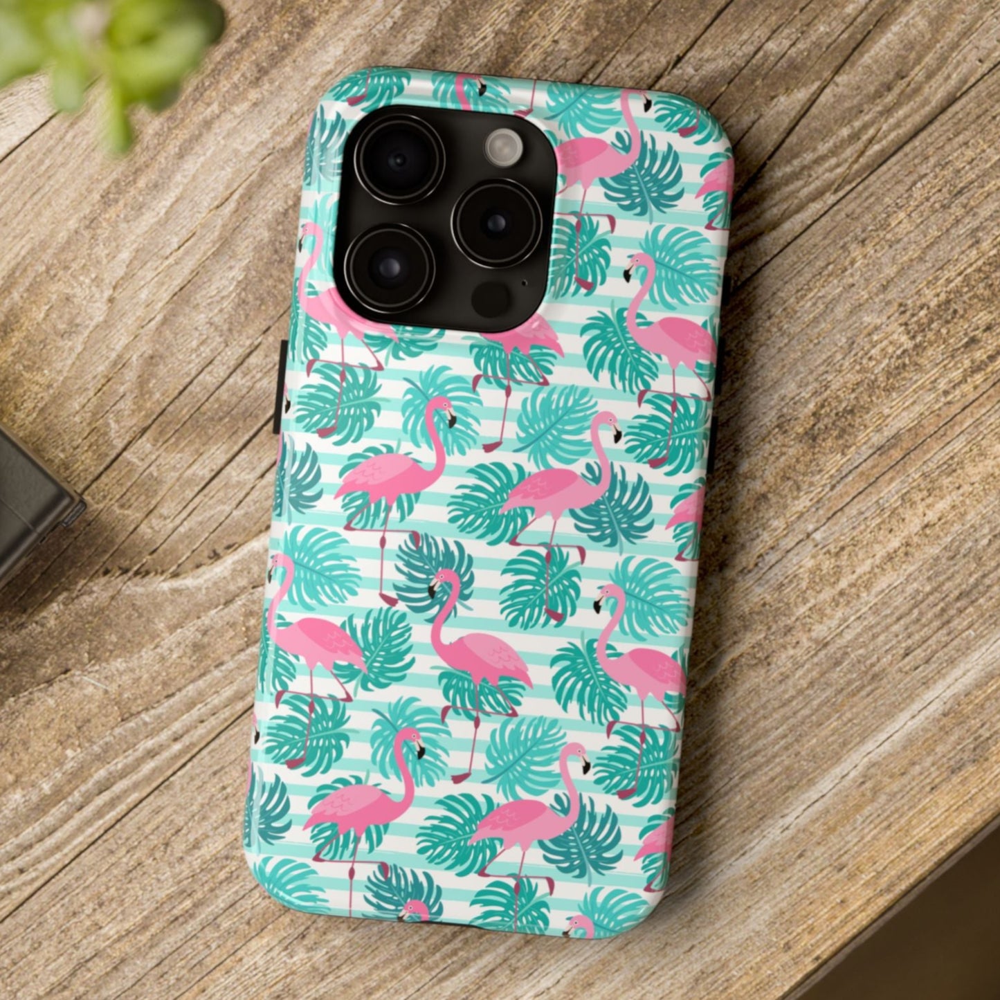 Phone case with flamingo and leaf pattern on a wooden surface