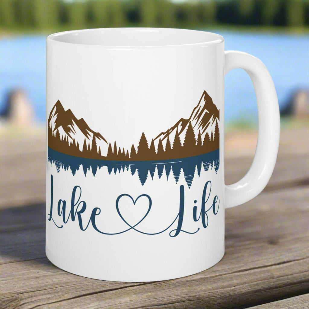 White 11 oz. ceramic mug with mountain and lake reflection design, featuring the phrase “Lake Life” – perfect for nature lovers.