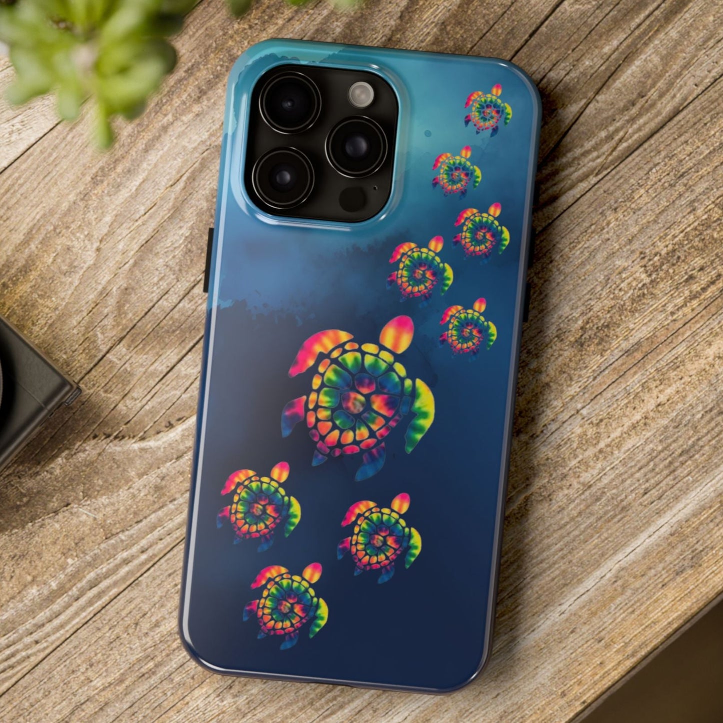 Phone case with colorful turtle design on a wooden surface