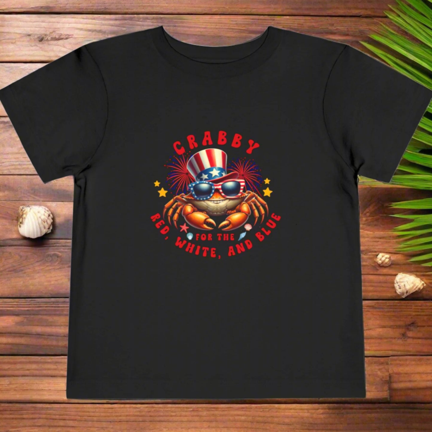 Black t-shirt with a colorful graphic of a crab wearing an American flag hat and sunglasses, with text 'CRABBY FOR THE RED, WHITE, AND BLUE' on a white background.