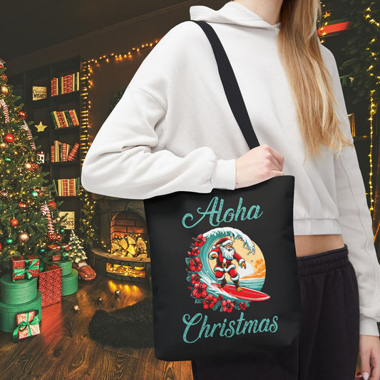Person holding a black tote bag with 'Aloha Christmas' design in a festive indoor setting.