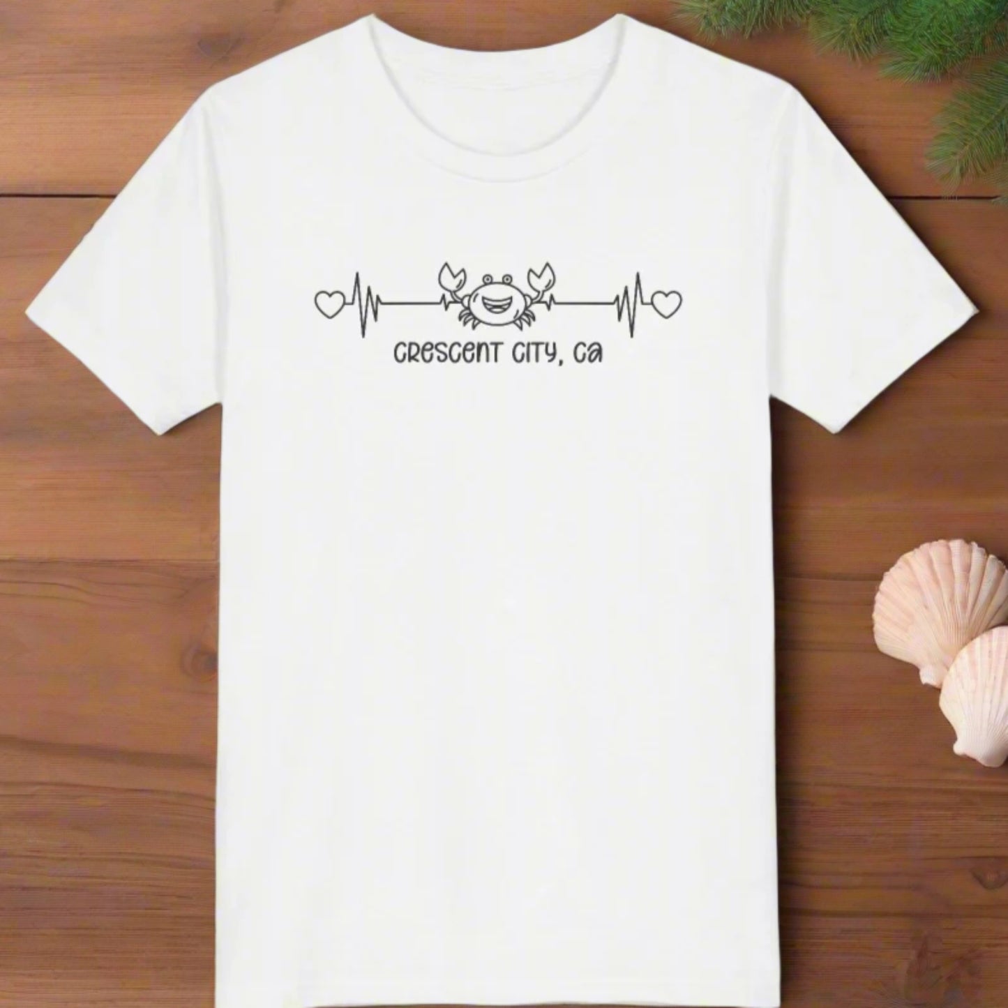 White Child t-shirt with a smiley crab on a heartbeat line with hearts at both ends and “Crescent City, CA” underneath the design.