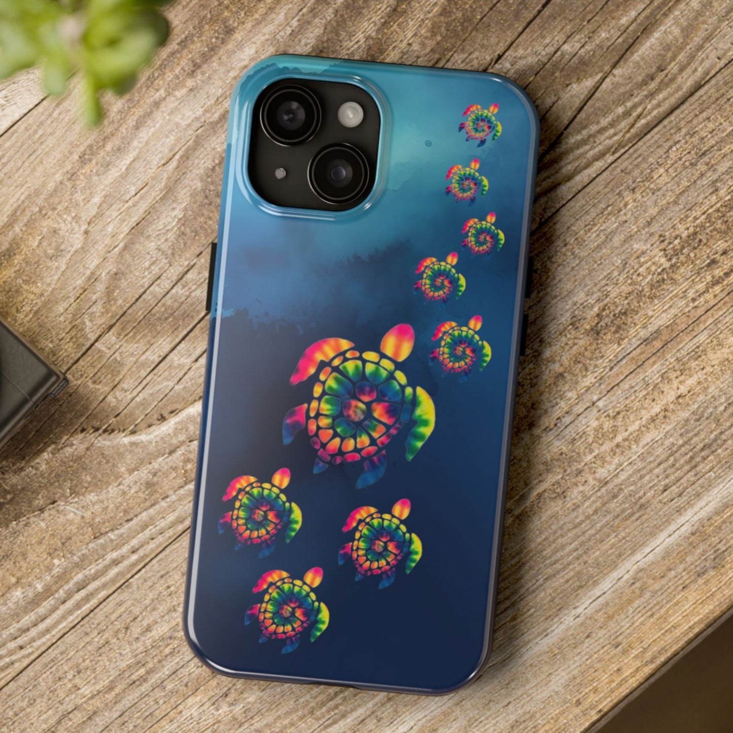 Phone case with colorful spiral design on a wooden surface next to a camera