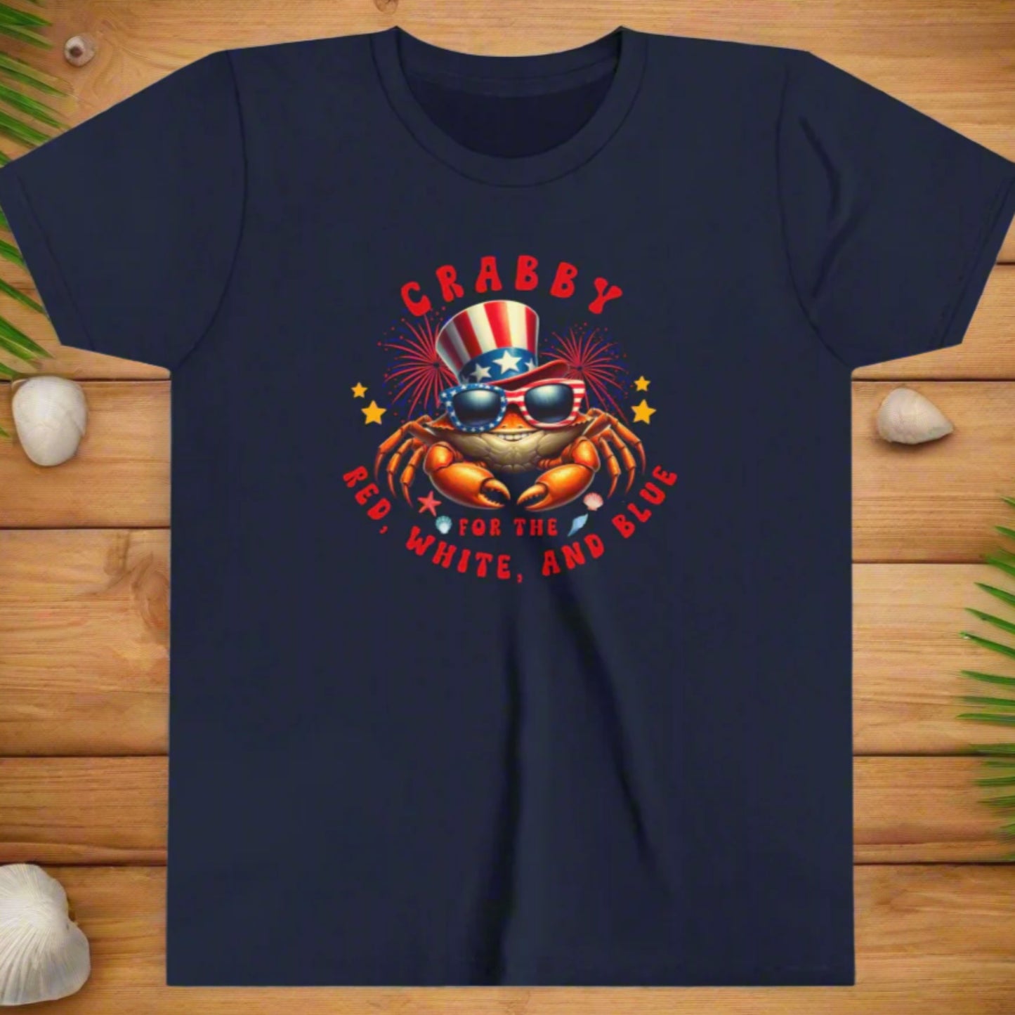 Navy blue t-shirt with a crab graphic wearing sunglasses and an American flag hat, text 'CRABBY FOR THE RED, WHITE, AND BLUE' on a white background.