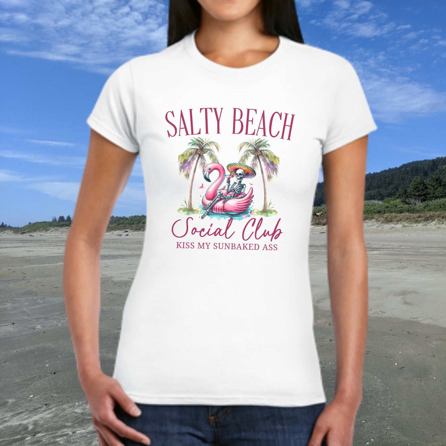 Person wearing a white t-shirt with 'Salty Beach Social Club' design on a beach.
