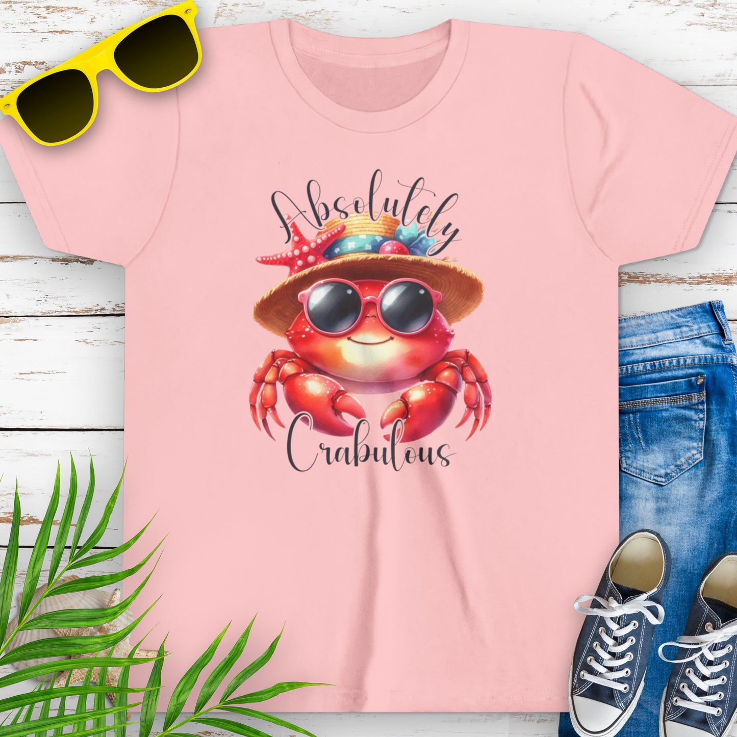 Pink t-shirt with a cartoon crab wearing sunglasses and a beach hat decorated with seashells, with the text “Absolutely Crabulous.”