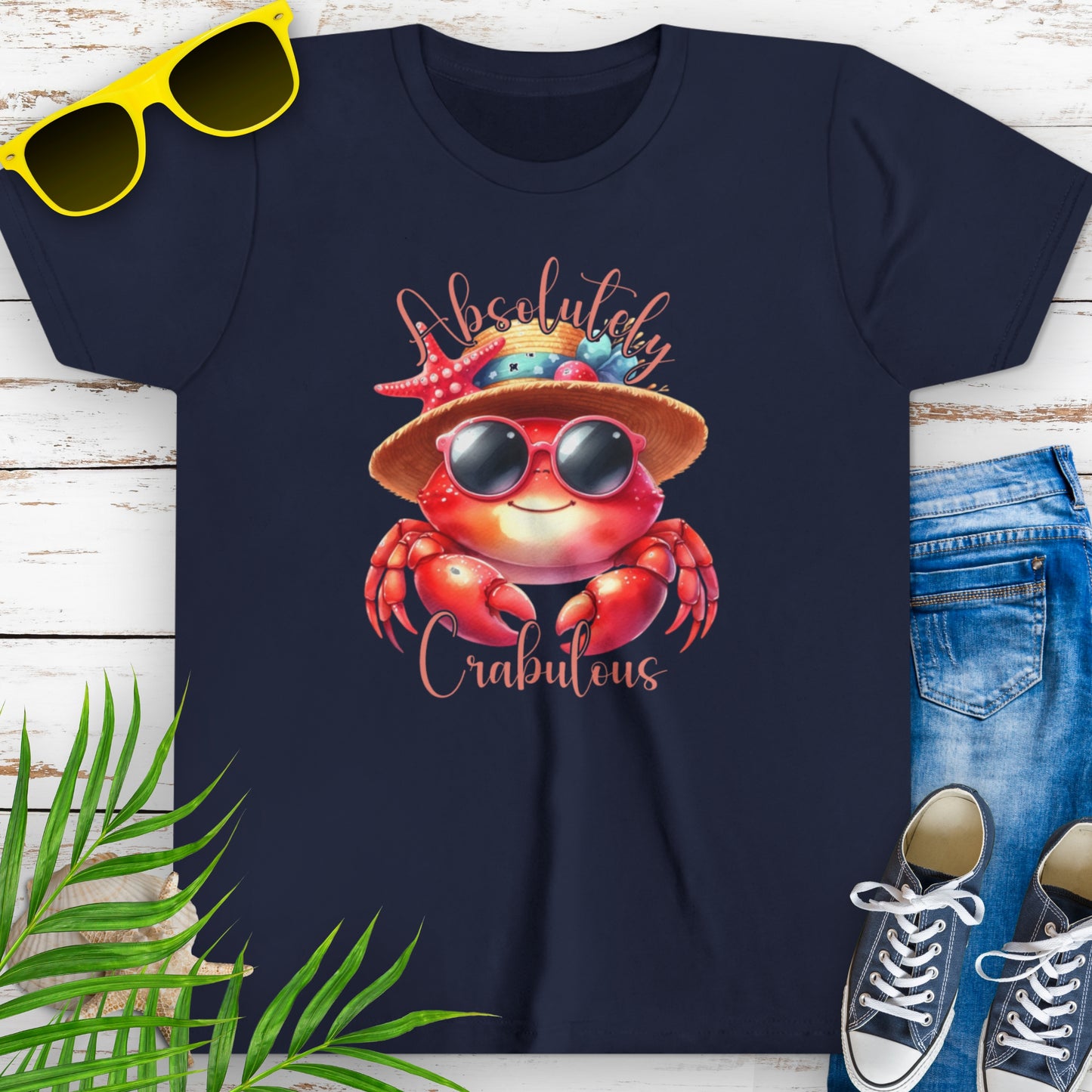 Navy blue t-shirt with a cartoon crab wearing sunglasses and a beach hat decorated with seashells, with the text “Absolutely Crabulous.”