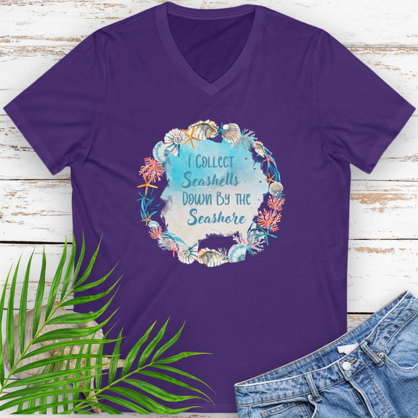 Purple v-neck t-shirt with a seashell wreath and the text 'I Collect Seashells Down By the Seashore'.