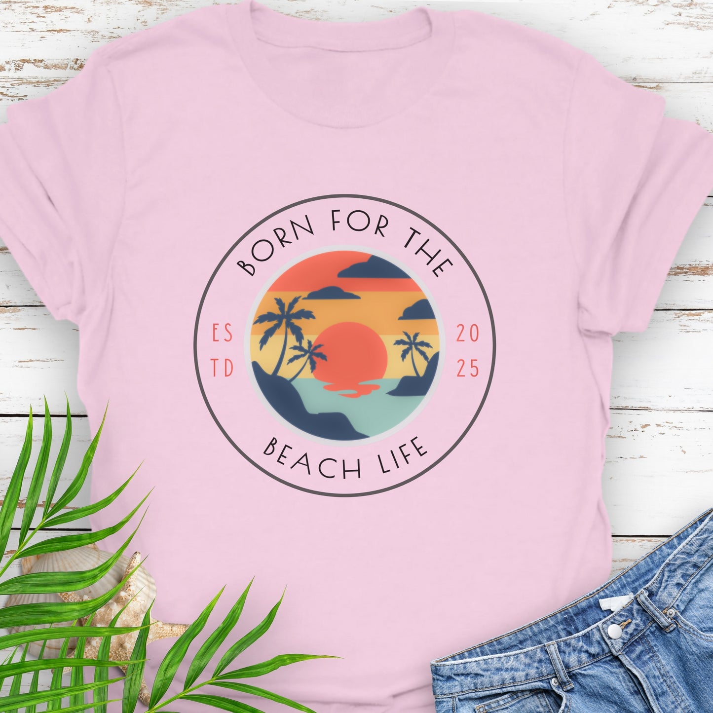 Pink t-shirt with circle design with a beach scene and the text “Born for the Beach Life.