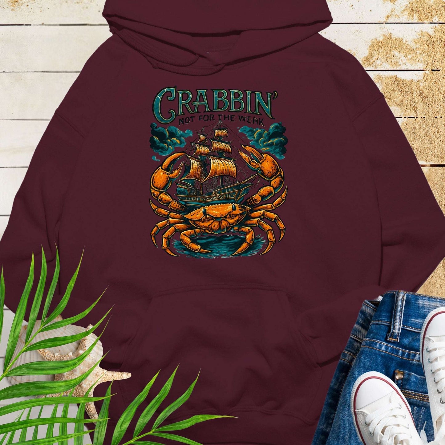 Maroon hoodie with a large crab enveloping a pirate ship with the text “Crabbin’s Not for the Weak” in an old-style font.