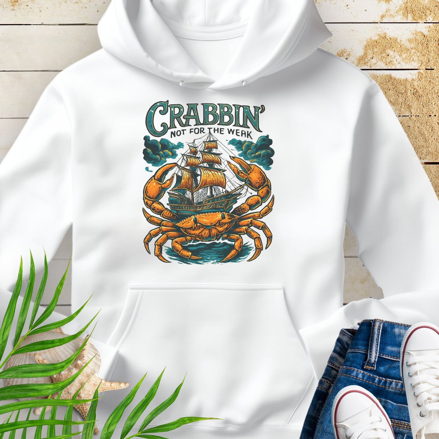 White hoodie with a large crab enveloping a pirate ship with the text “Crabbin’s Not for the Weak” in an old-style font.
