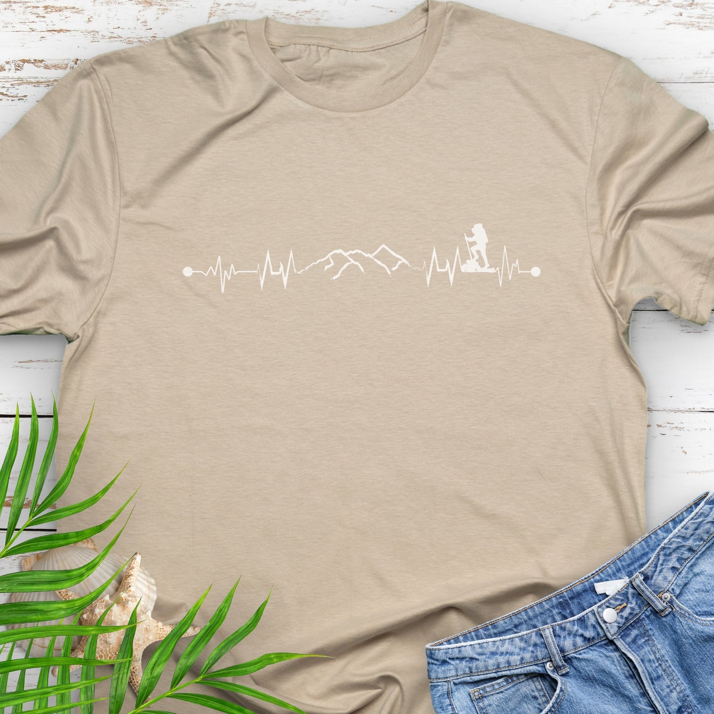 Beige t-shirt with a heartbeat line with a mountain range and backpacker.