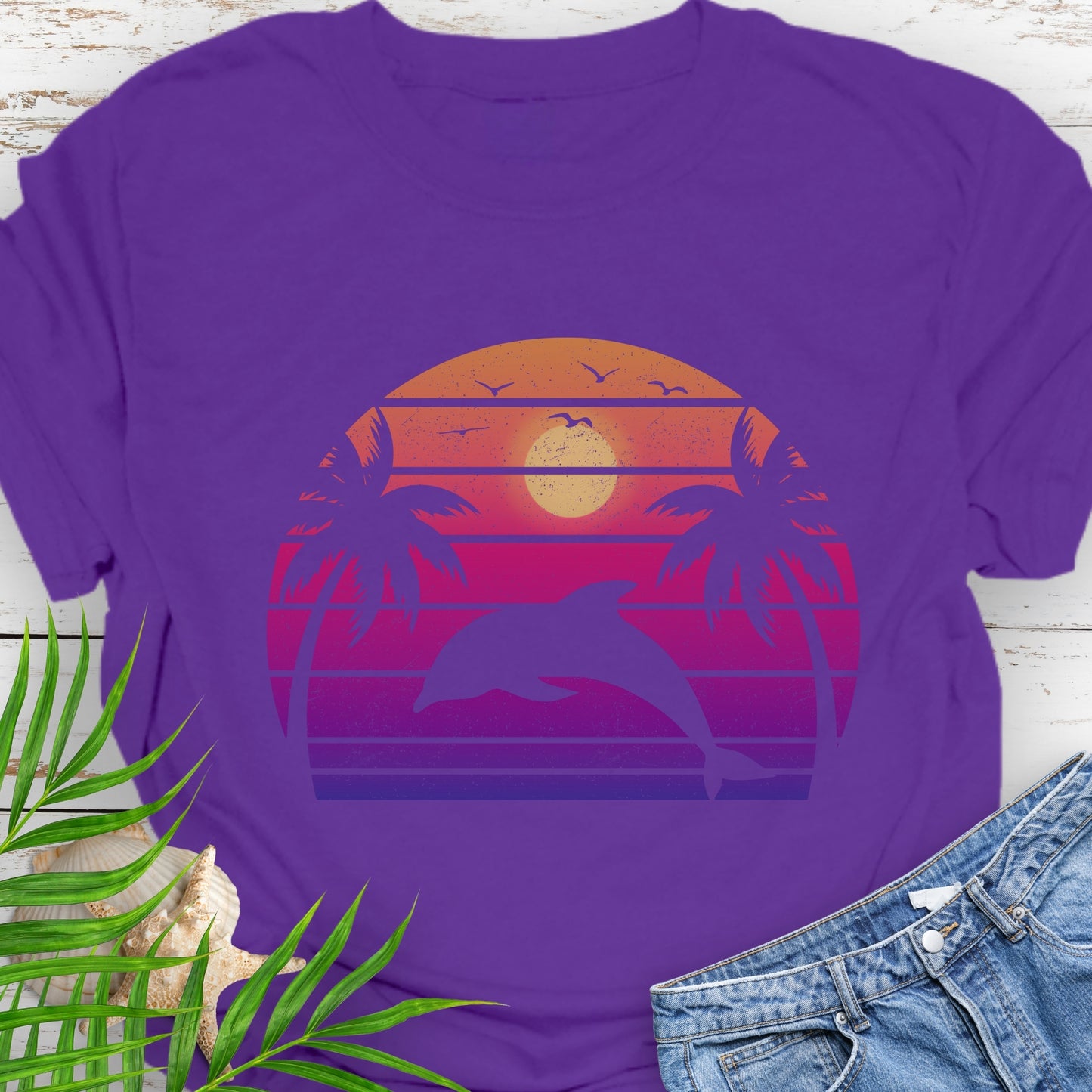 Purple T-shirt with a dolphin against a retro sunset and two palm trees.