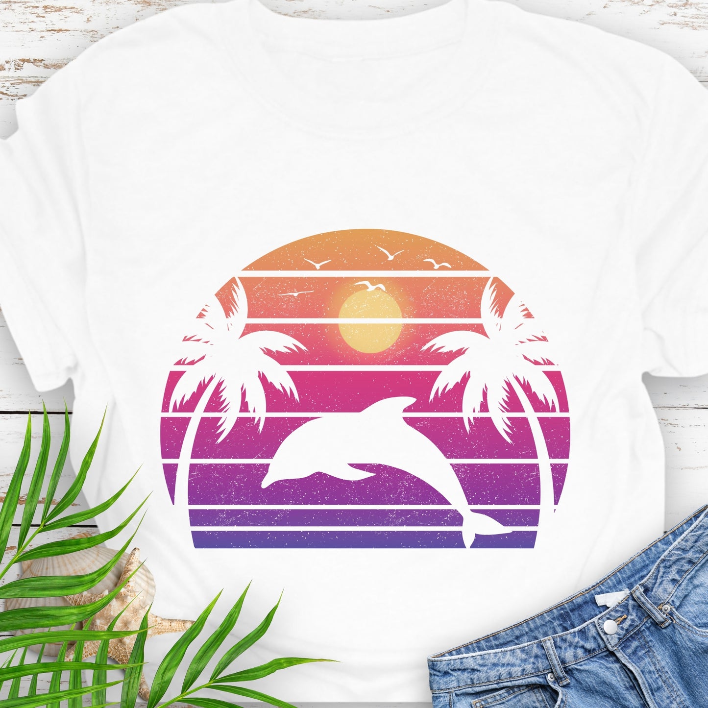 White T-shirt with a dolphin against a retro sunset and two palm trees.