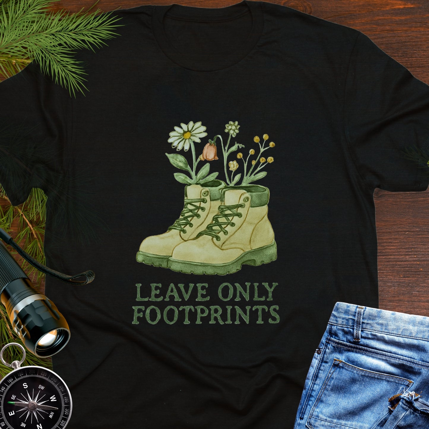 Black T-shirt with hiking boots and wildflowers that says "Leave Only Footprints."