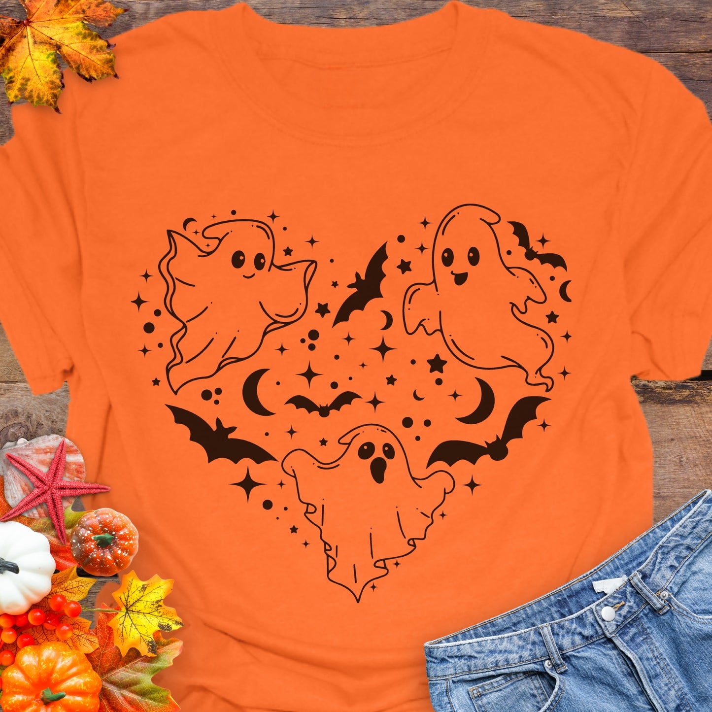 Orange unisex T-shirt with a design of white ghosts and black bats forming the shape of a heart.