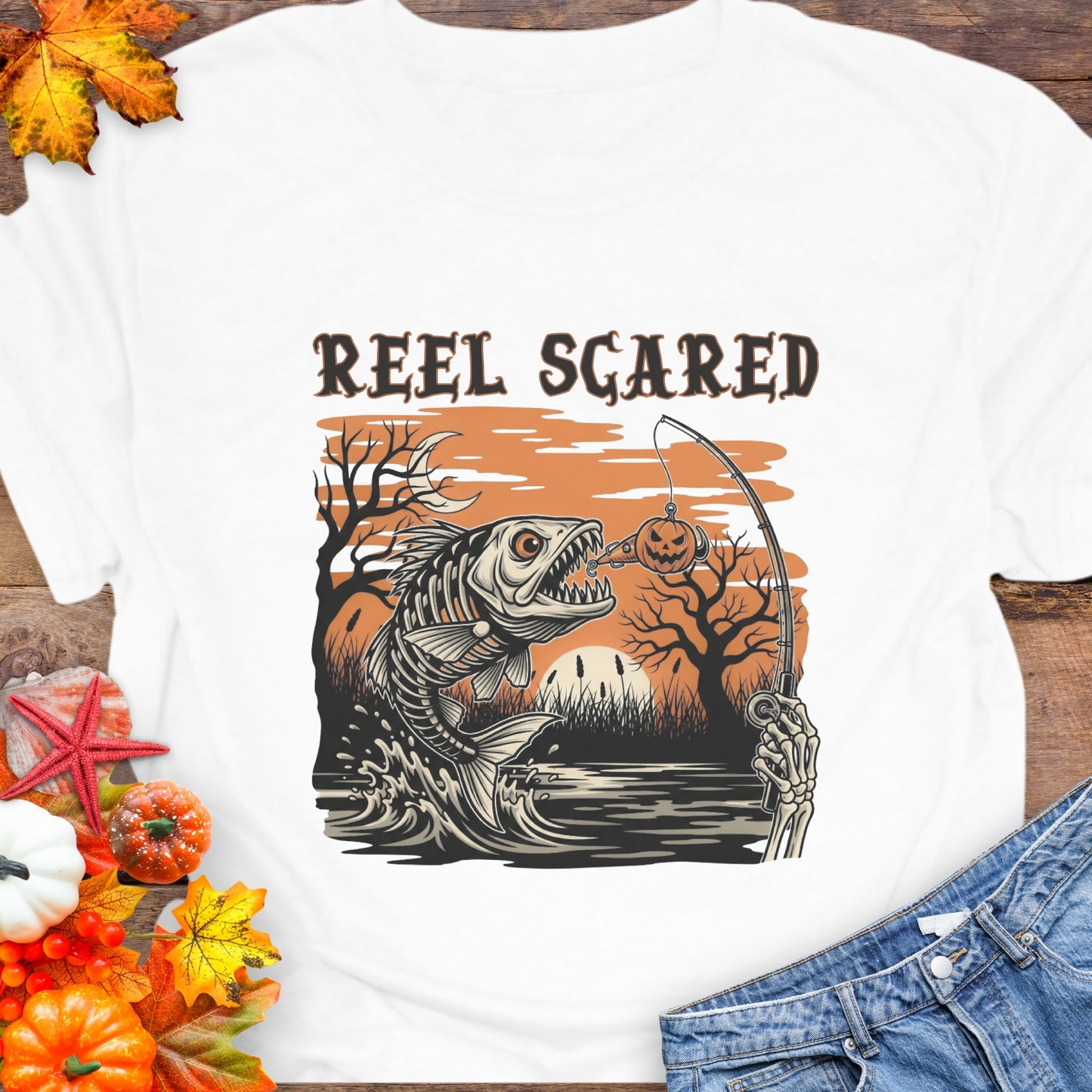 White T-shirt with a skeleton fish going for a hook and the phrase “Reel Scared.