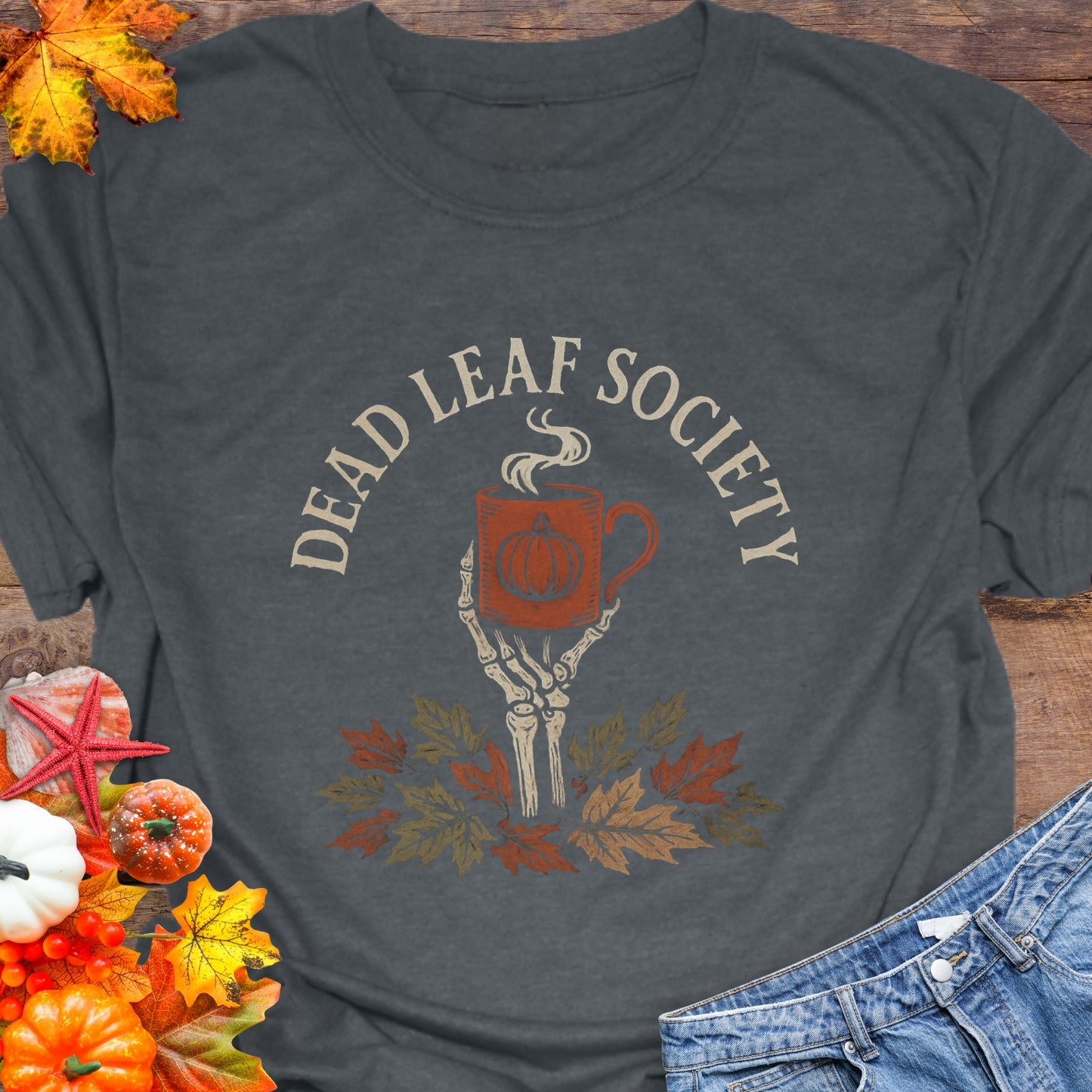 Gray t-shirt with a skeleton hand holding a coffee cup above fall leaves and the text “Dead Leaf Society.”