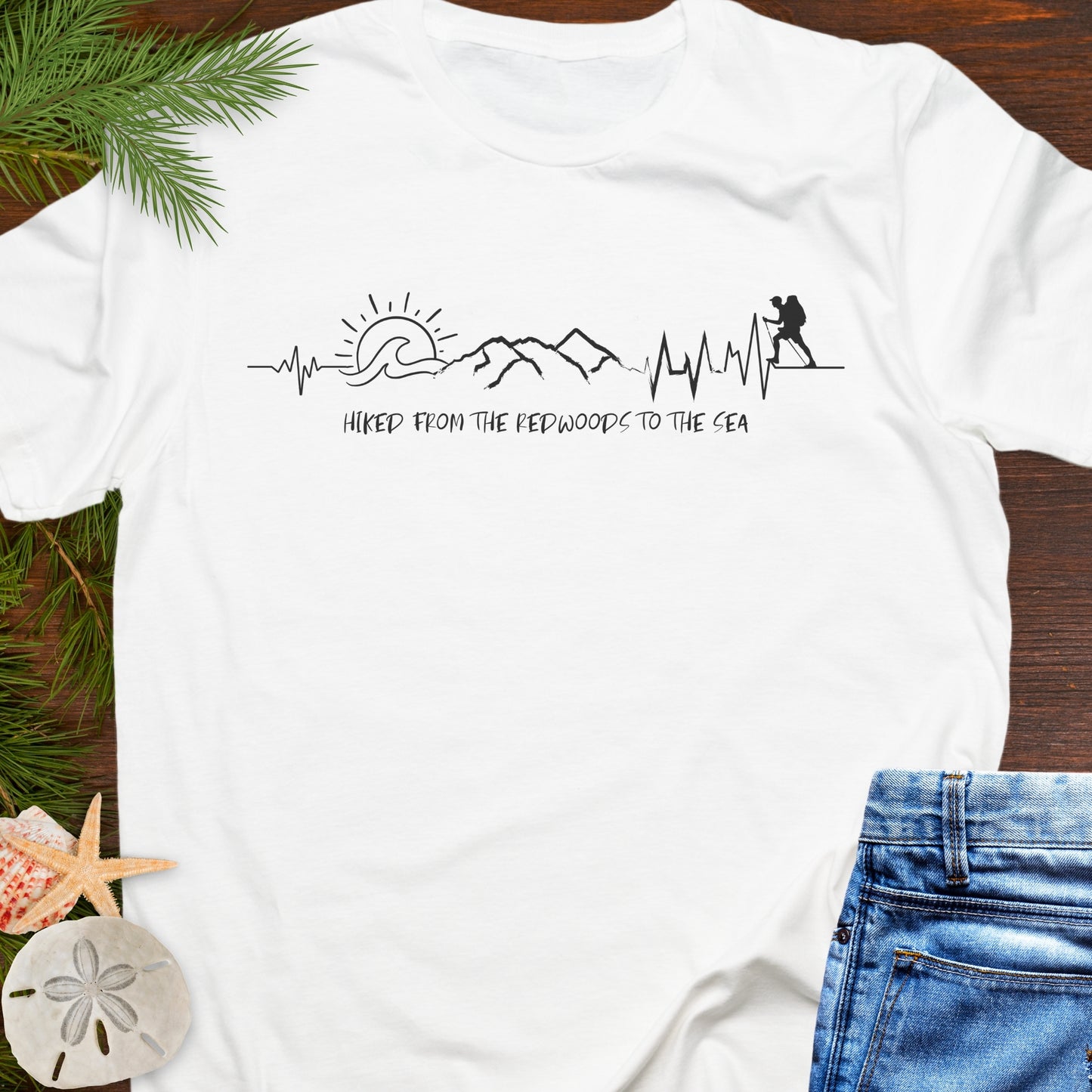 White t-shirt with white hiking heartline graphic design with text Hiked from the Redwoods to the sea.