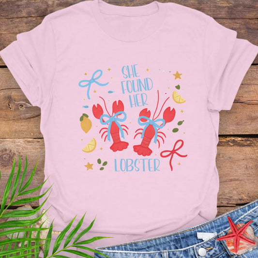 Pink T-shirt with two lobsters and blue bows that says She Found Her Lobster.
