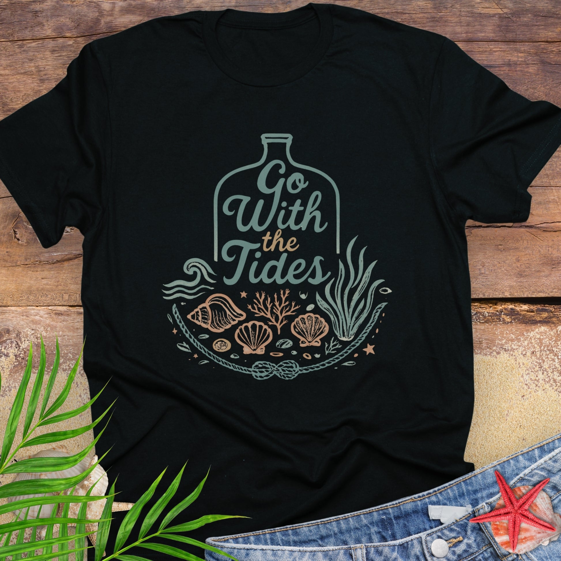 Black Go With the Tides t-shirt with ocean bottle design, seashells, and coral artwork.