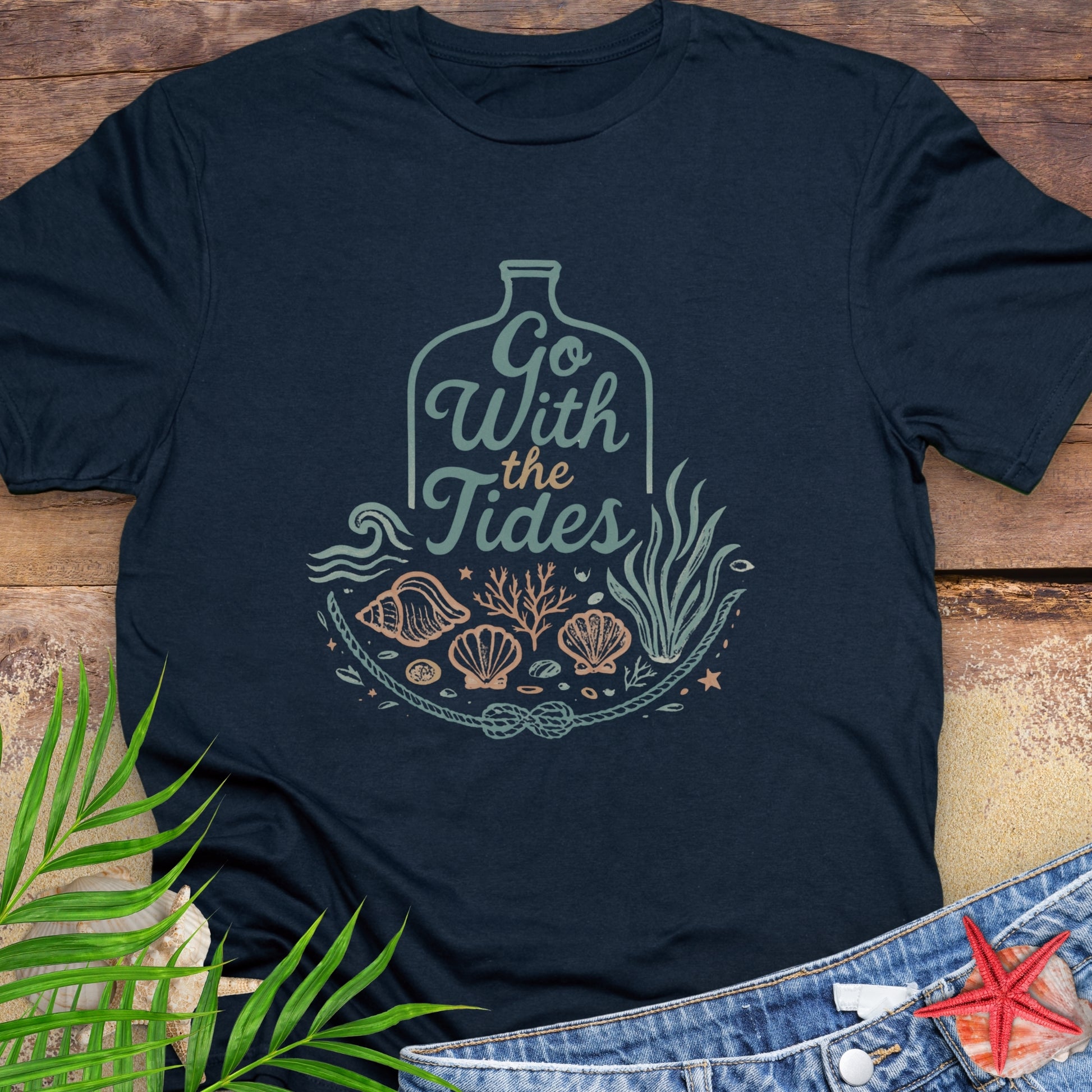 Navy blue Go With the Tides t-shirt with ocean bottle design, seashells, and coral artwork.