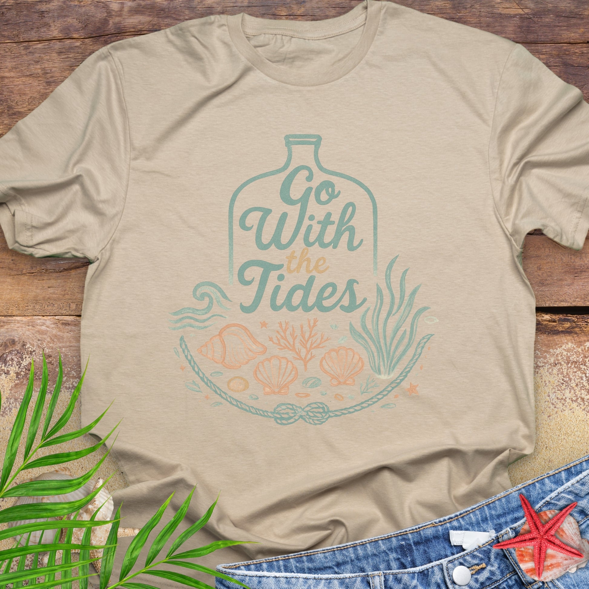 Beige Go With the Tides t-shirt with ocean bottle design, seashells, and coral artwork.