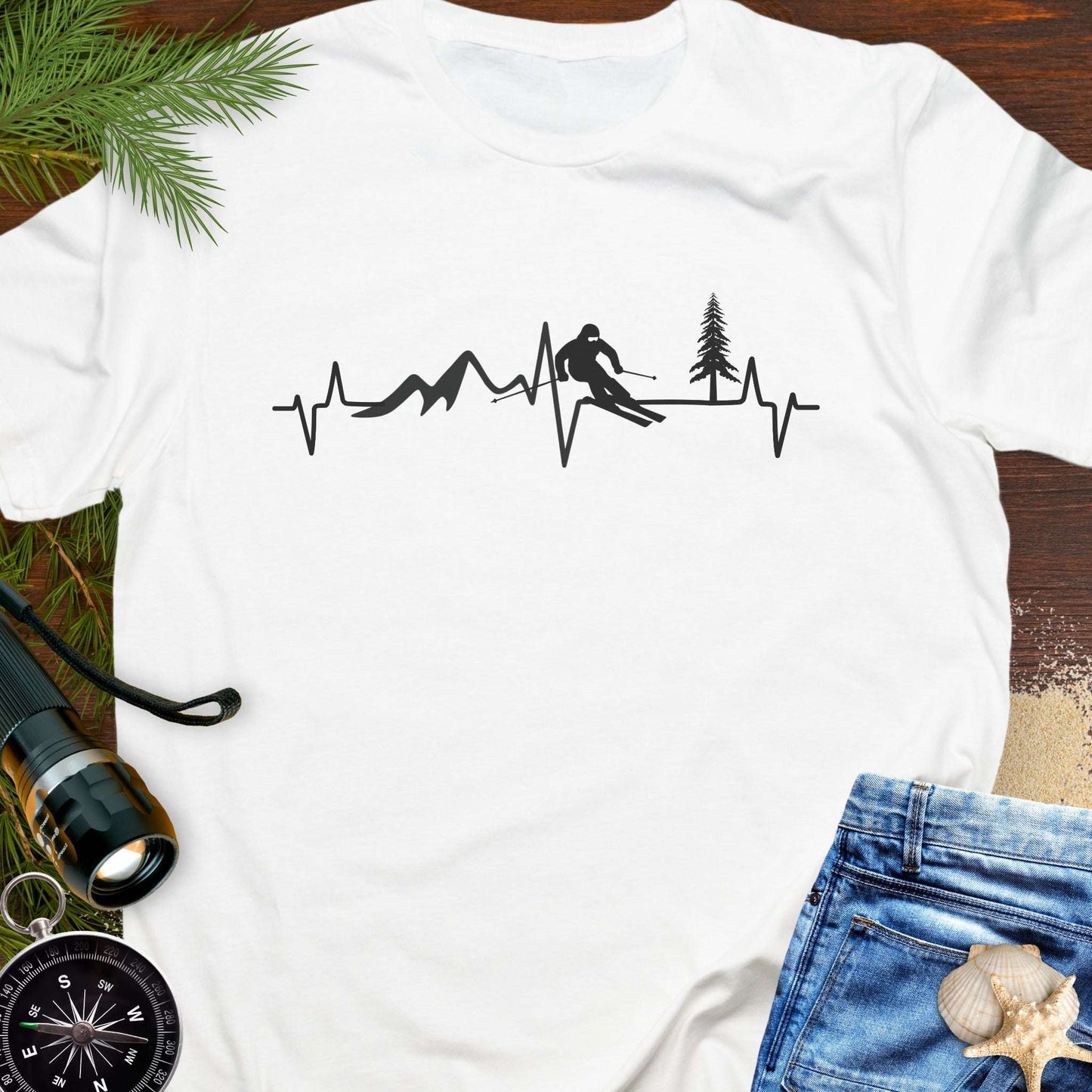 White t-shirt with a black silhouette design of a skier, trees, and mountains on a heartline.