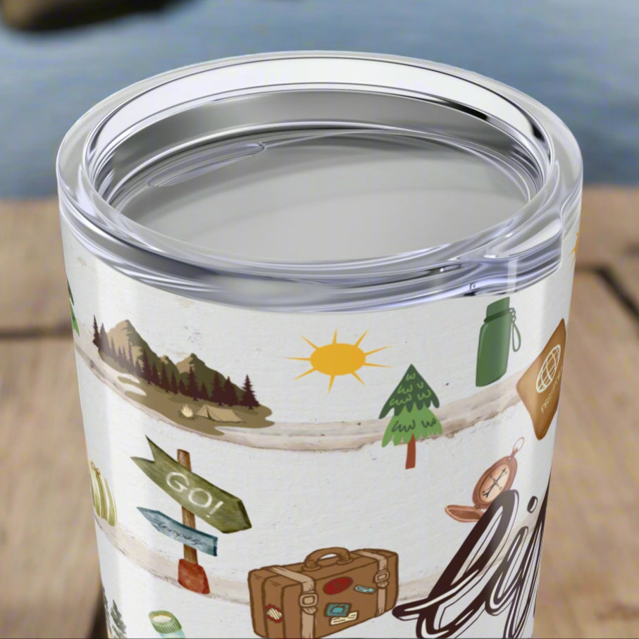 Top view of clear lid on 20oz stainless steel tumbler with “Life is an Adventure” text and wraparound print featuring tents, compass, trees, sun, lantern, and camping icons.