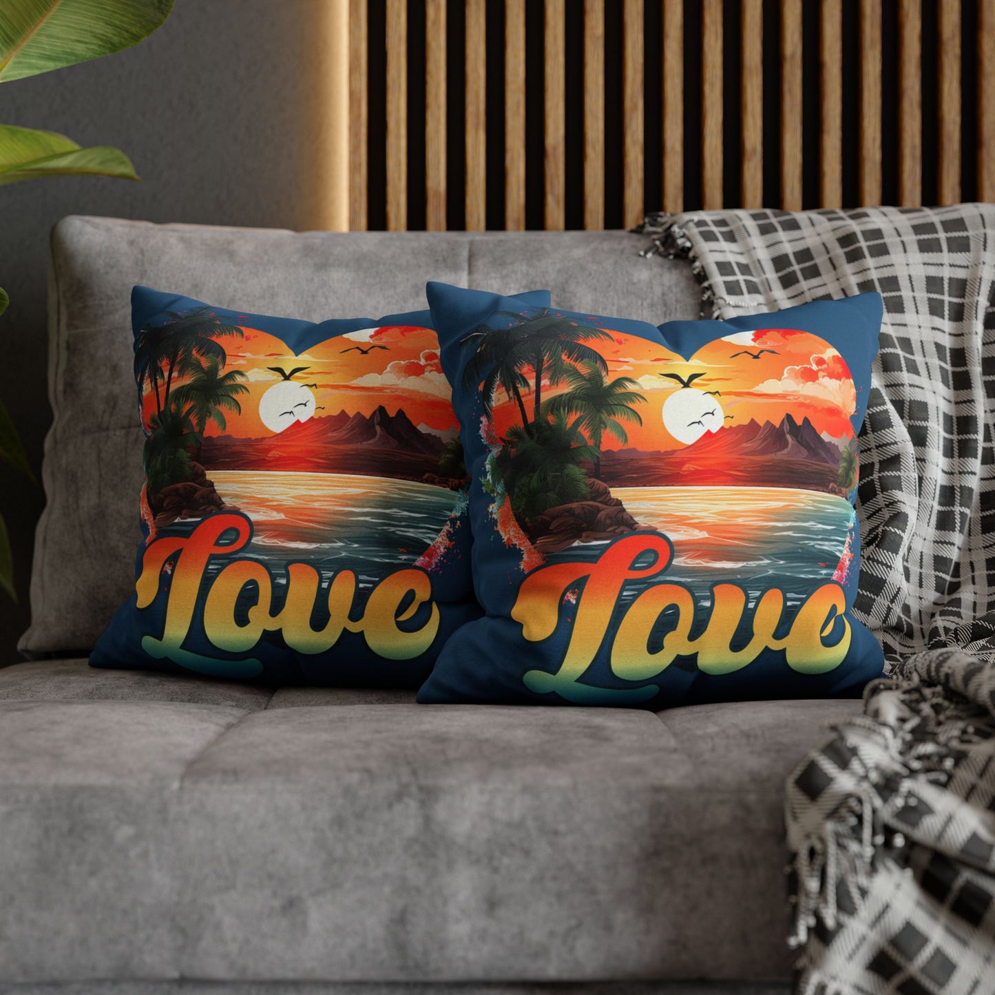 Two decorative 16" x 16" blue pillows with a sunset heart design and 'love' text on a gray couch.