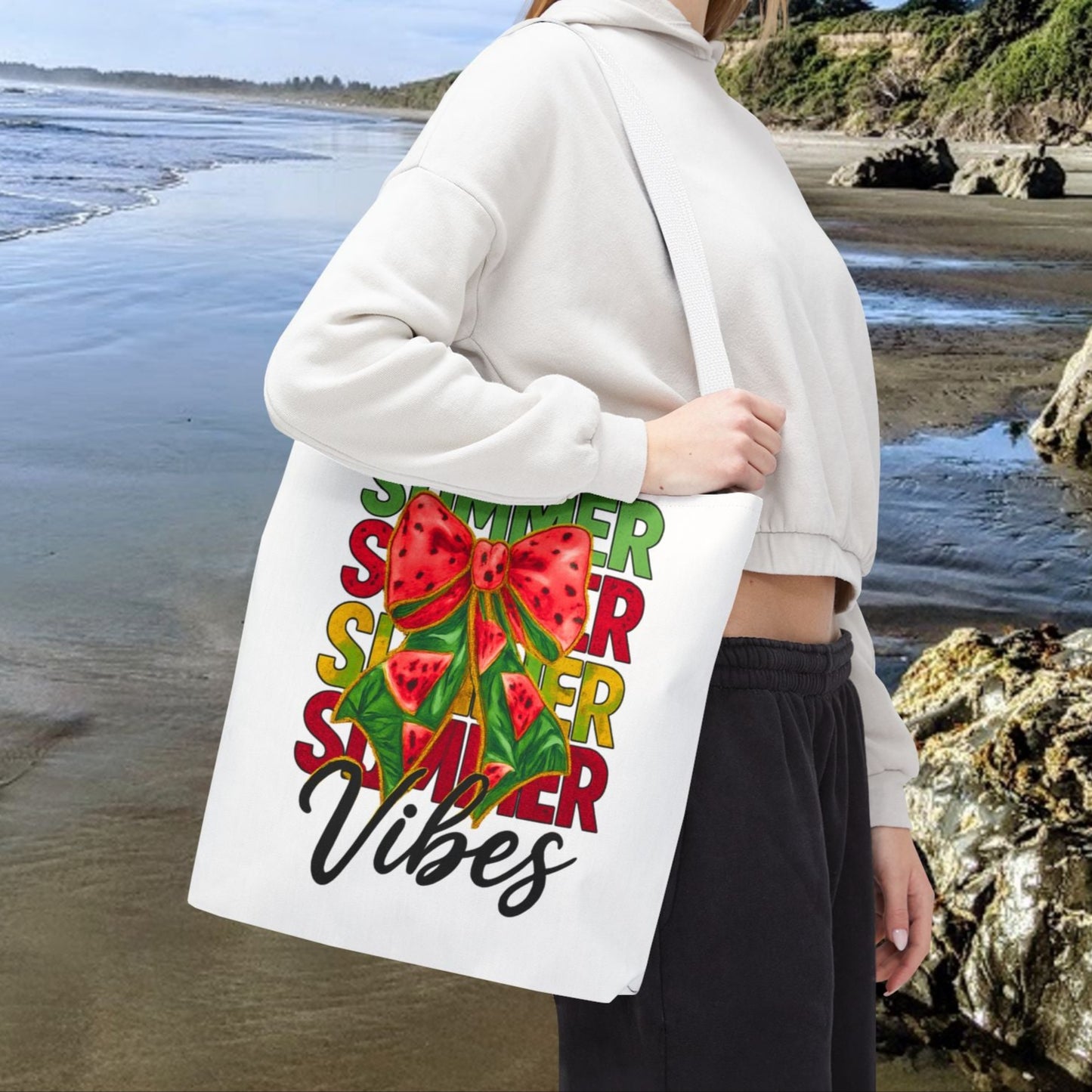 White 16" x 16" tote bag with the word "Summer" repeated in green, red, and yellow, featuring a coquette-style bow, watermelon illustrations, and the word "Vibes" underneath.
