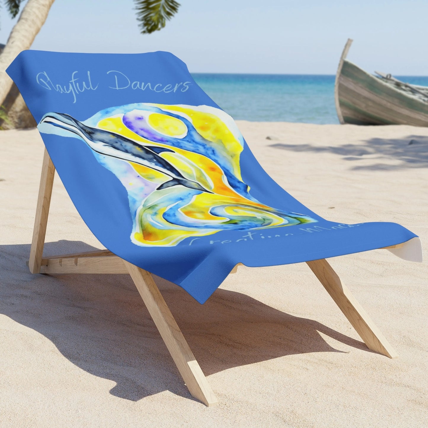 Blue beach towel with abstract dolphin image with yellow and blue background with the phrase Playful Dancers Creating Magic laying on a lounge chair on the beach.