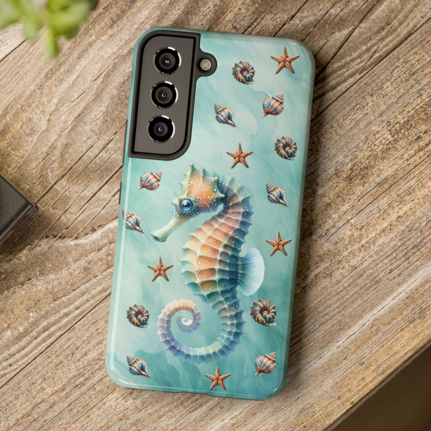 Phone case with seahorse design on a wooden surface