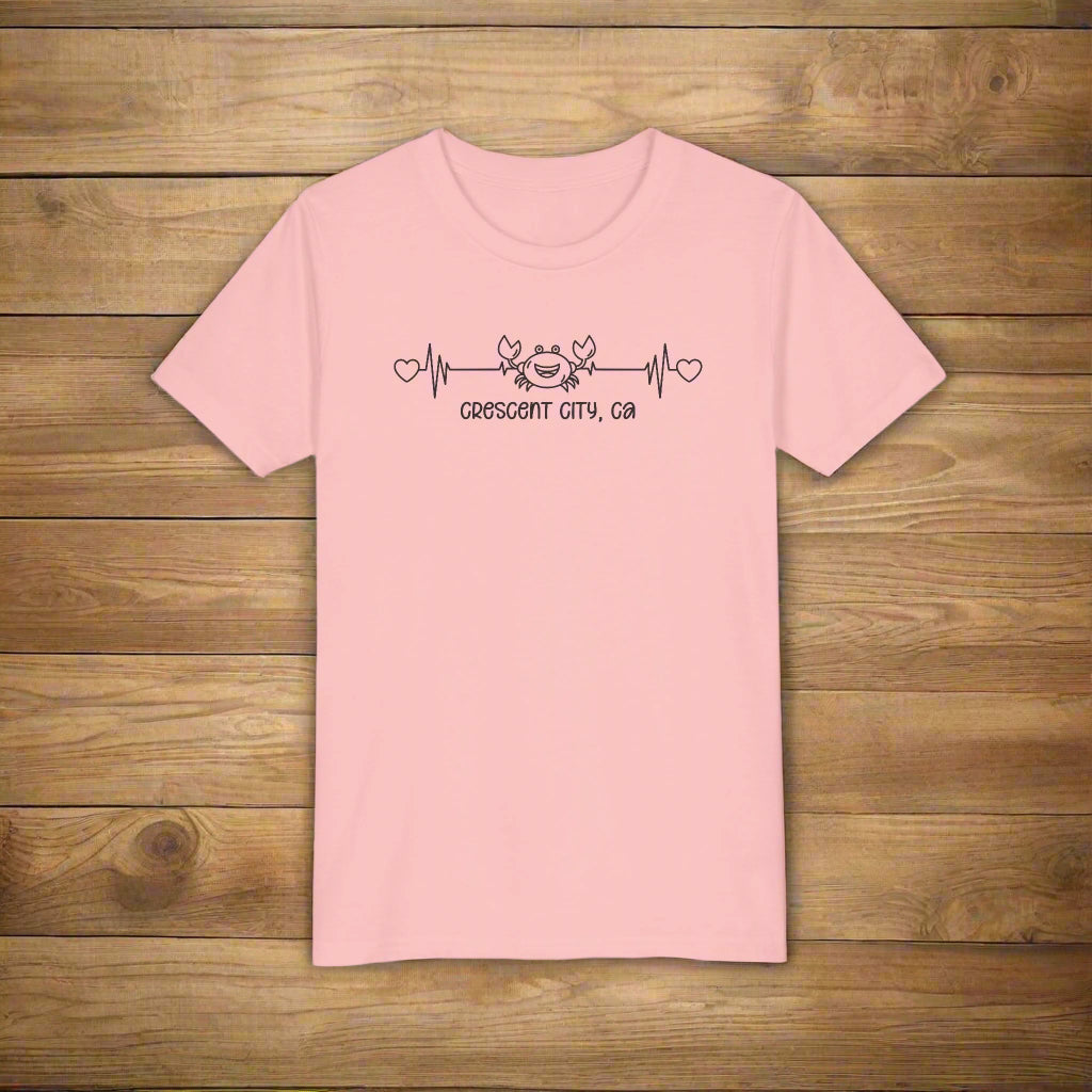 Pink Child t-shirt with a smiley crab on a heartbeat line with hearts at both ends and “Crescent City, CA” underneath the design.