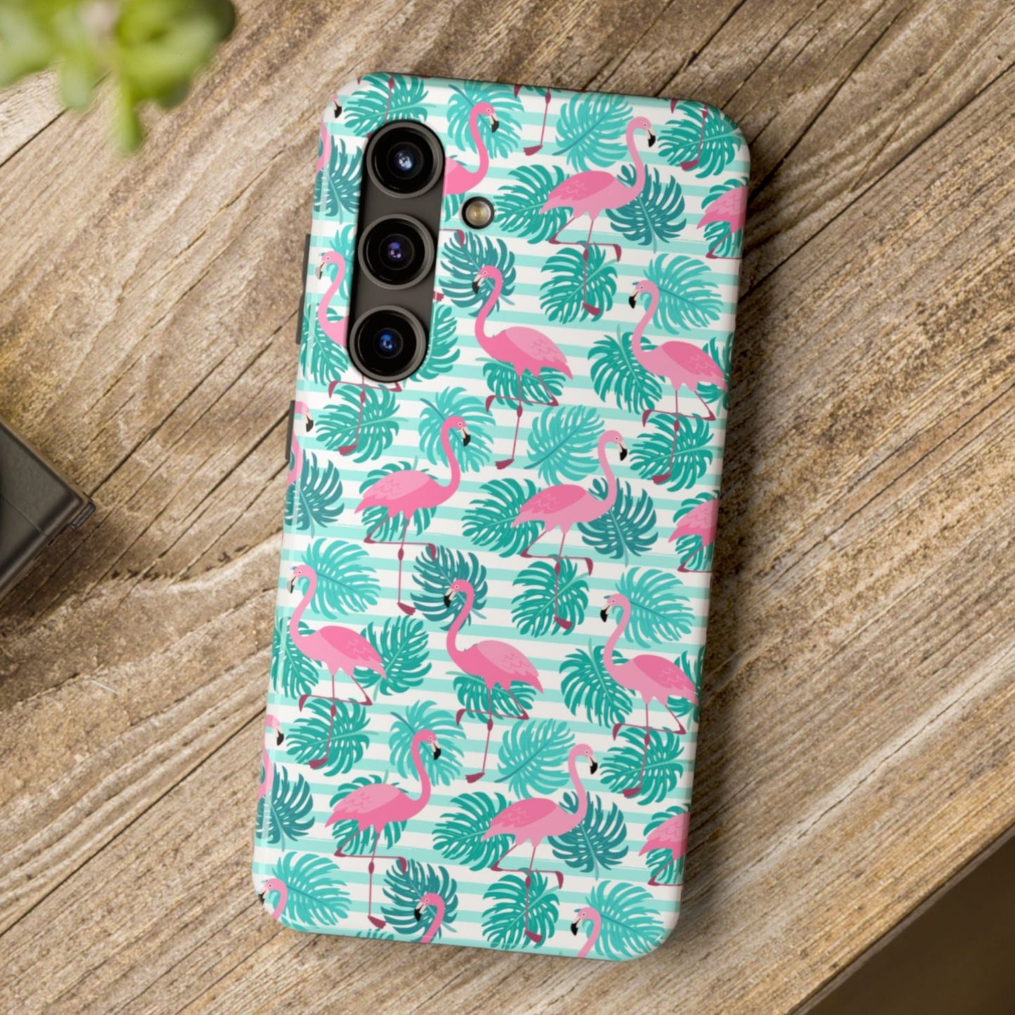 Phone case with flamingo and leaf pattern on a wooden surface